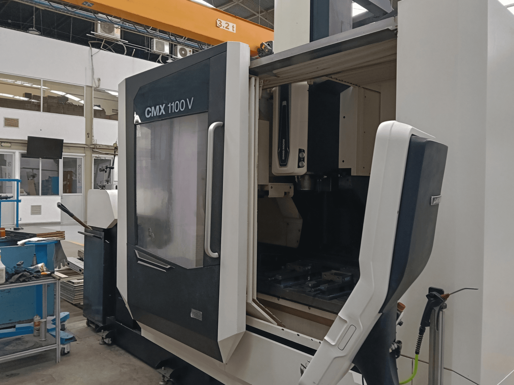 Vertikalni obradni centar DMG MORI CMX 1100 V, prednji pogled s otvorenim vratima i unutarnjim postavljanjem alata u industrijskom prostoru.