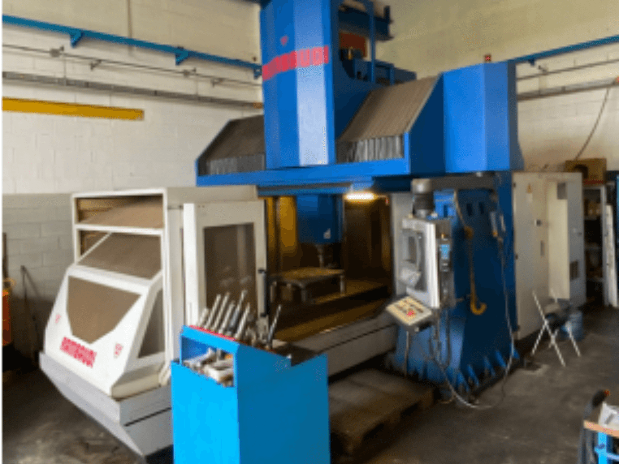 Vertikalni obradni centar Rambaudi RF103, prednji pogled s prikazom kontrola, spremišta alata i područja obrade. Plavo-bijeli vanjski dio.