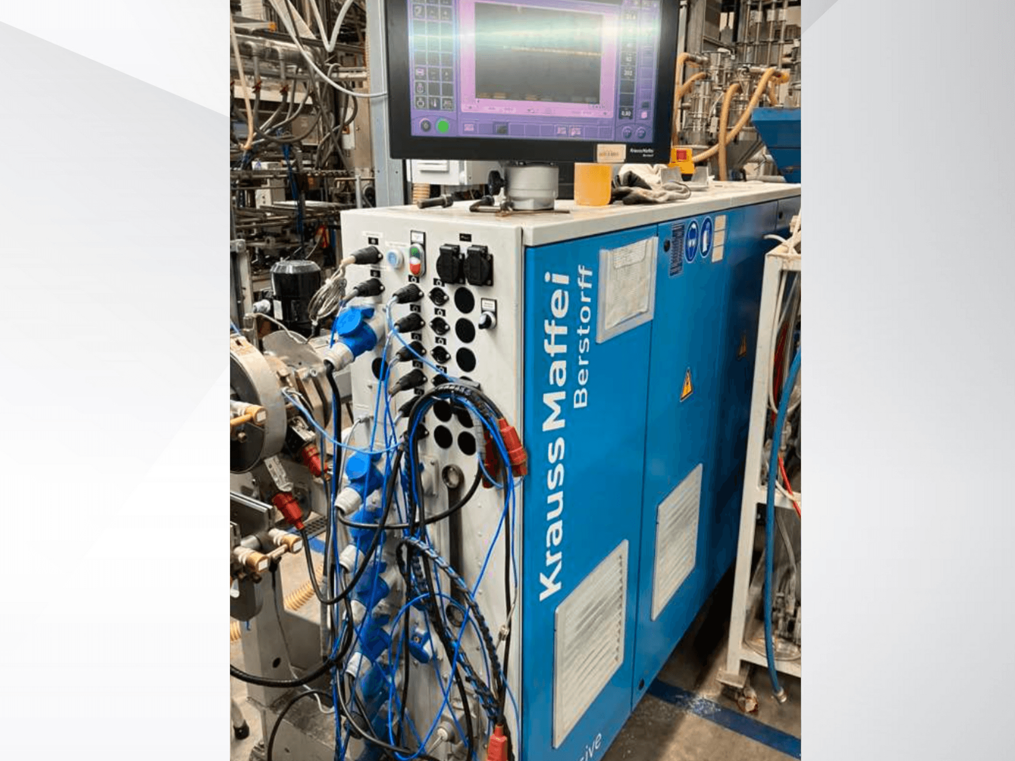 Industrijski stroj Krauss Maffei Berstorff s upravljačkom pločom i monitorom, s raznim gumbima i spojenim crijevima, bočni pogled.