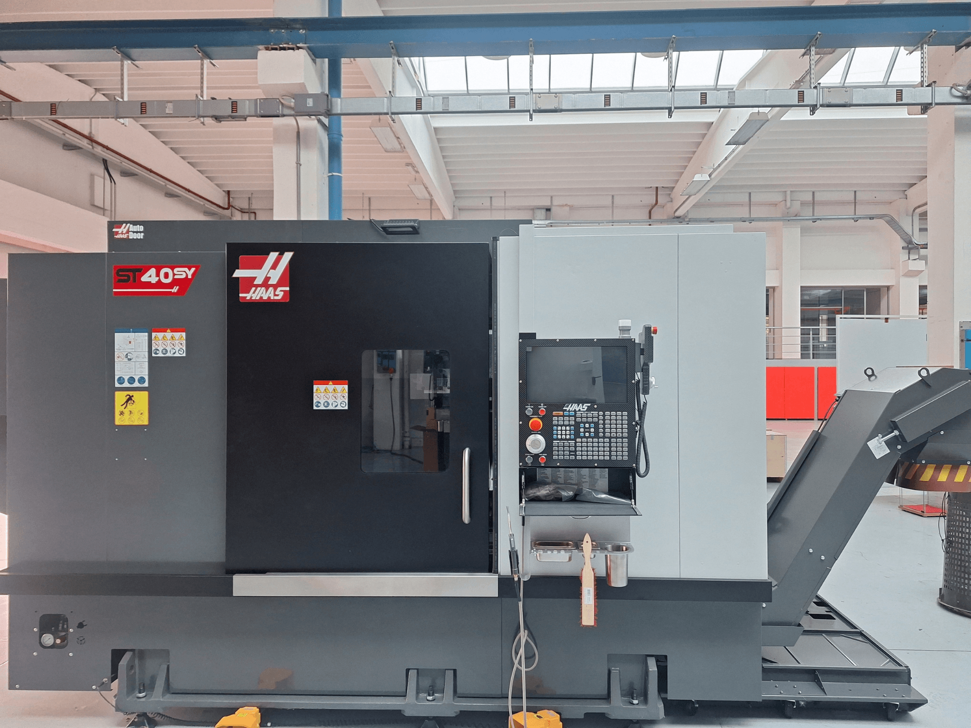 Haas ST-40SY horizontalni tokarski stroj u bočnom pogledu, s upravljačkom pločom i sigurnosnim naljepnicama.