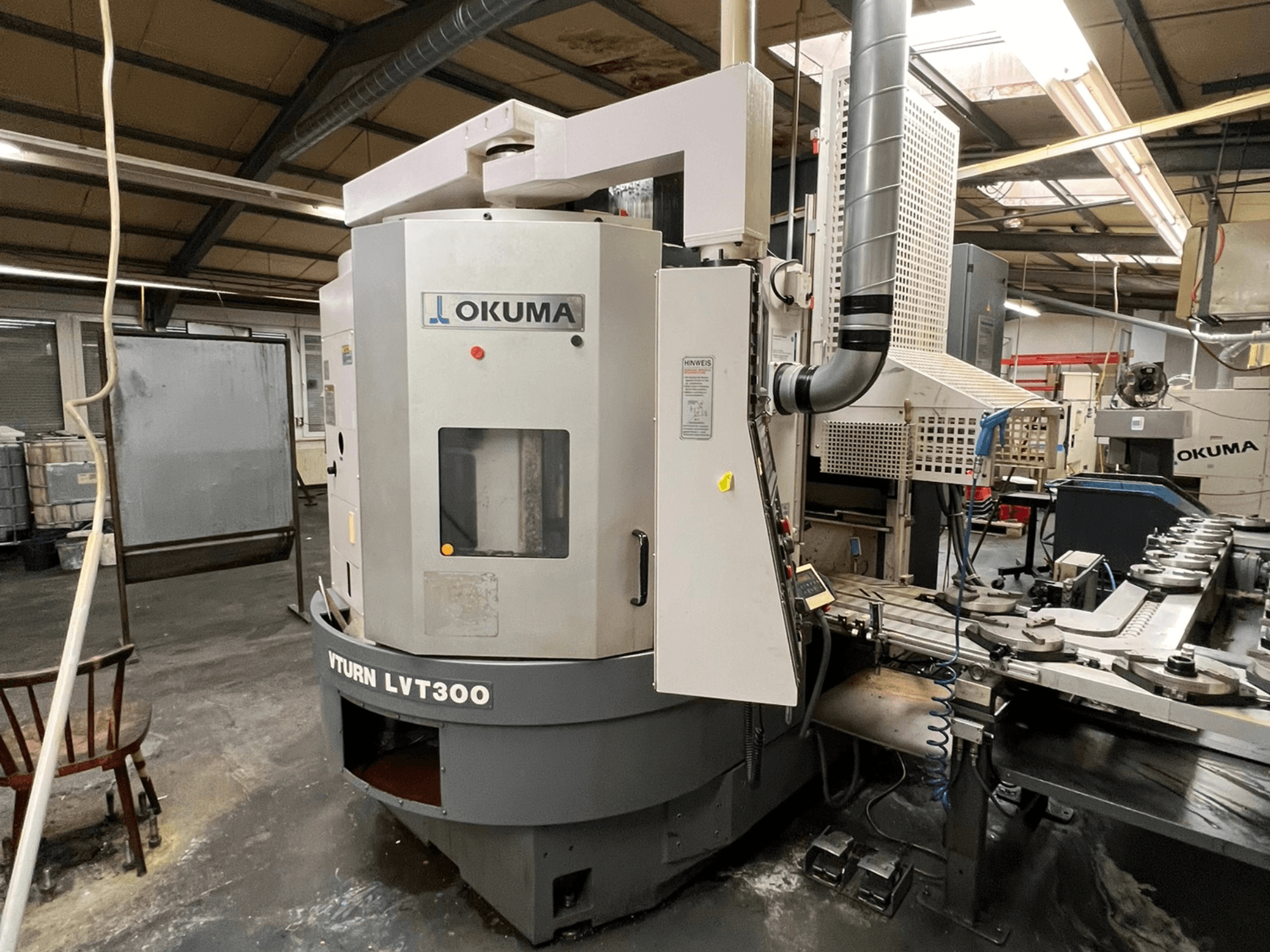Okuma Vturn LVT300 CNC tokarilica, bočni pogled u industrijskom okruženju, s prikazom upravljačke ploče i sustava rashladnog sredstva.