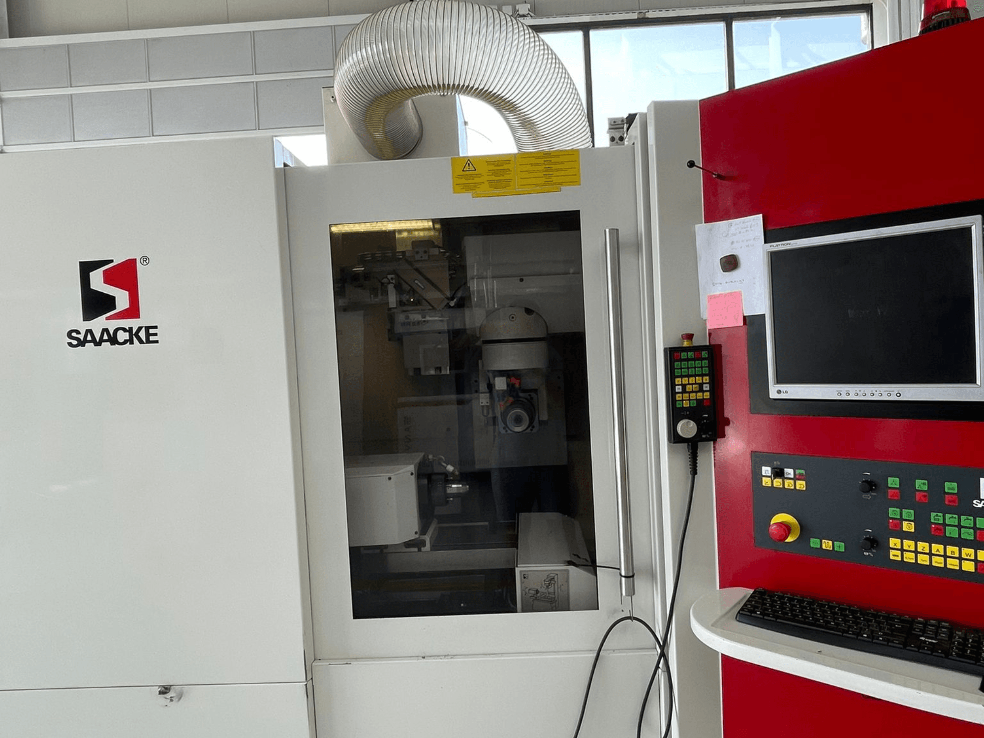 SAACKE stroj u bijeloj i crvenoj boji, pogled sprijeda, ima upravljačku ploču, monitor i vidljive unutarnje dijelove kroz staklo.