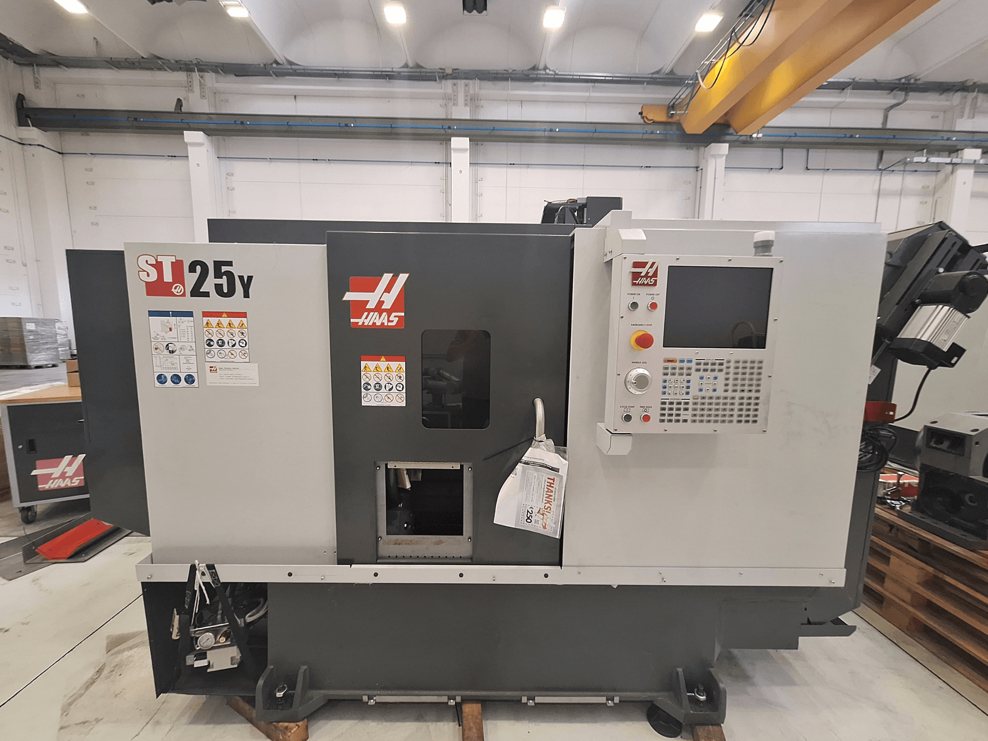 Haas ST-25Y horizontalni tokarski stroj, prednji pogled, ima upravljačku ploču i sigurnosne naljepnice. Idealan za preciznu obradu.