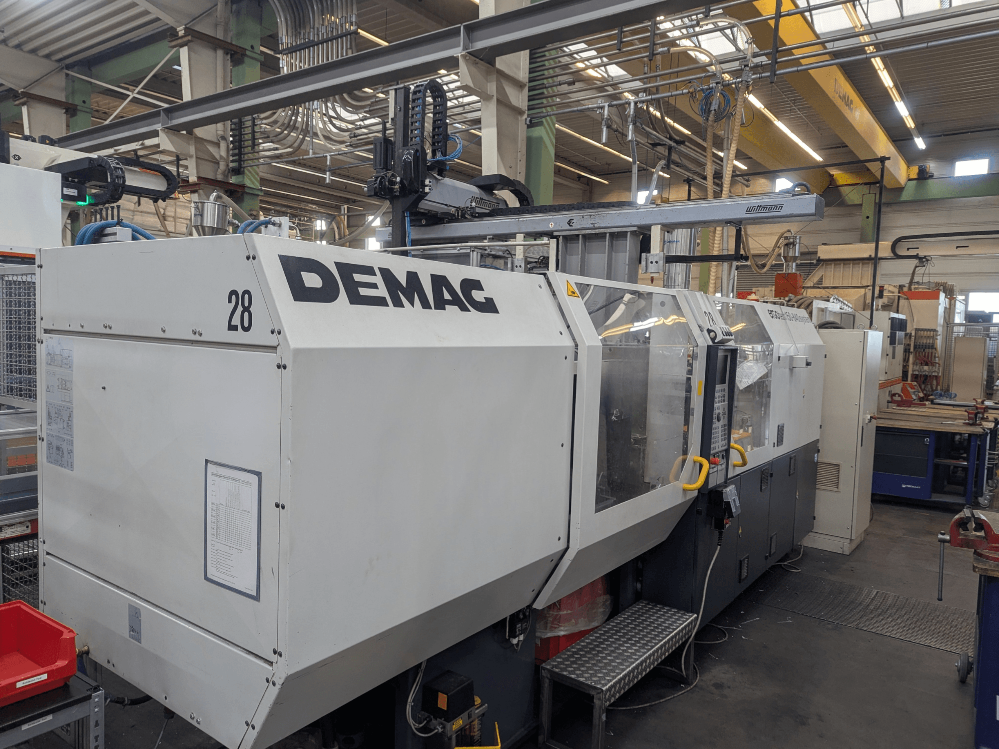 Prednji pogled na hidraulički stroj za brizganje plastike DEMAG ERGOTECH 1500-840, s prikazom operativnih kontrola i sigurnosnih značajki.