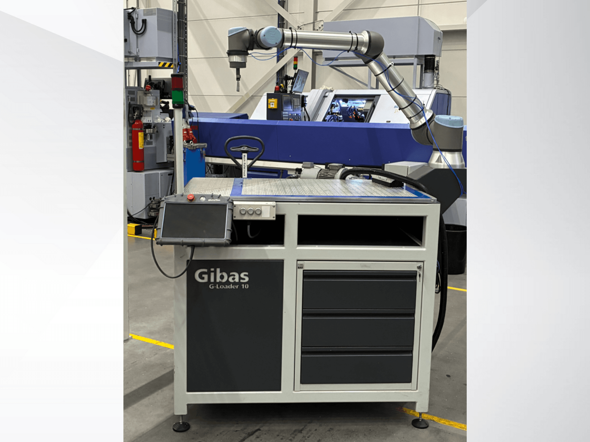 Gibas G-Loader 10 s robotskom rukom, prednji pogled; ima upravljanje putem zaslona osjetljivog na dodir i ladicu za pohranu u industrijskom okruženju.