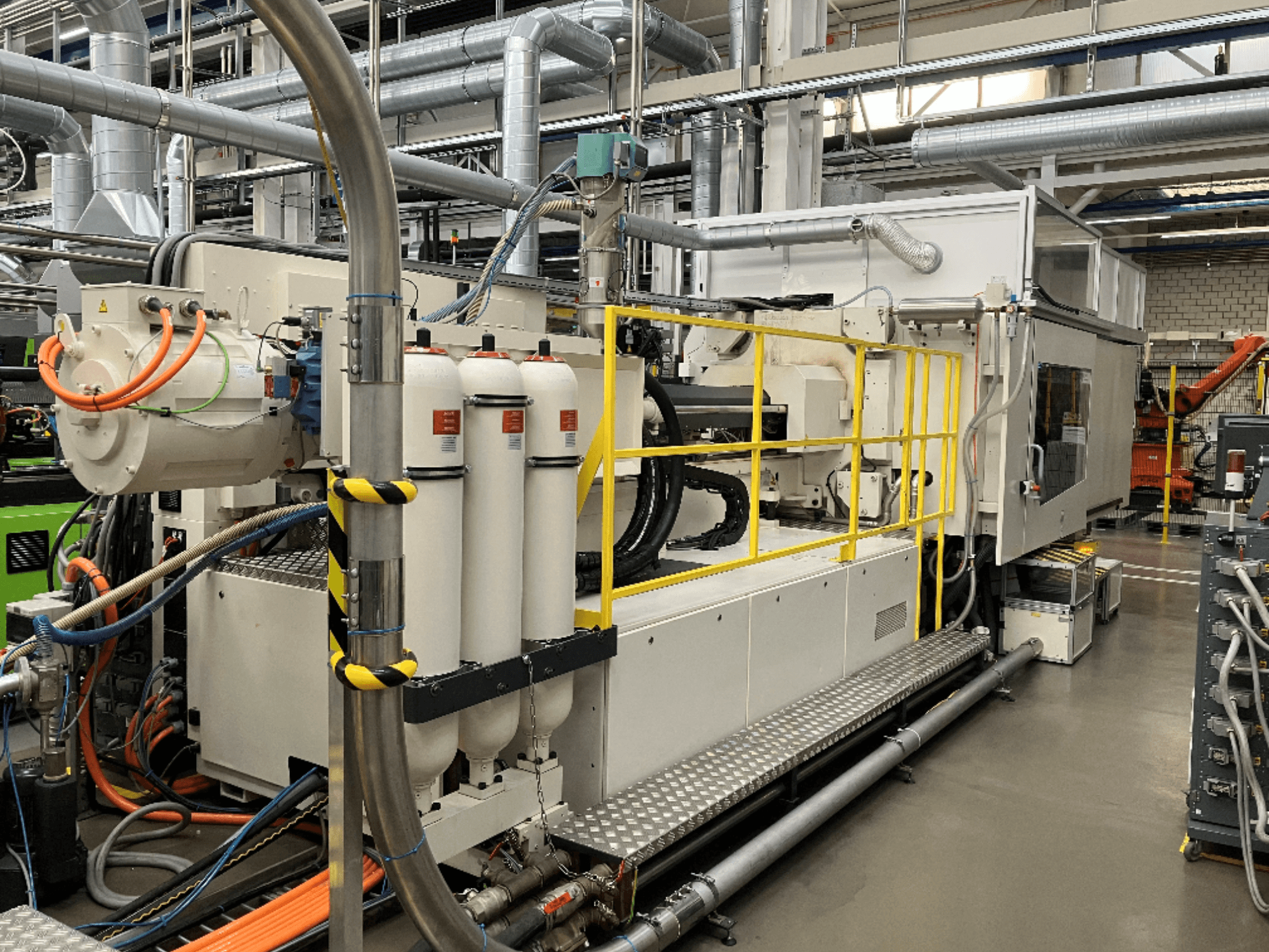 Industrijski stroj s bijelim i sivim kućištem, više crijeva i filterskih spremnika; bočni pogled koji prikazuje operativne postavke.