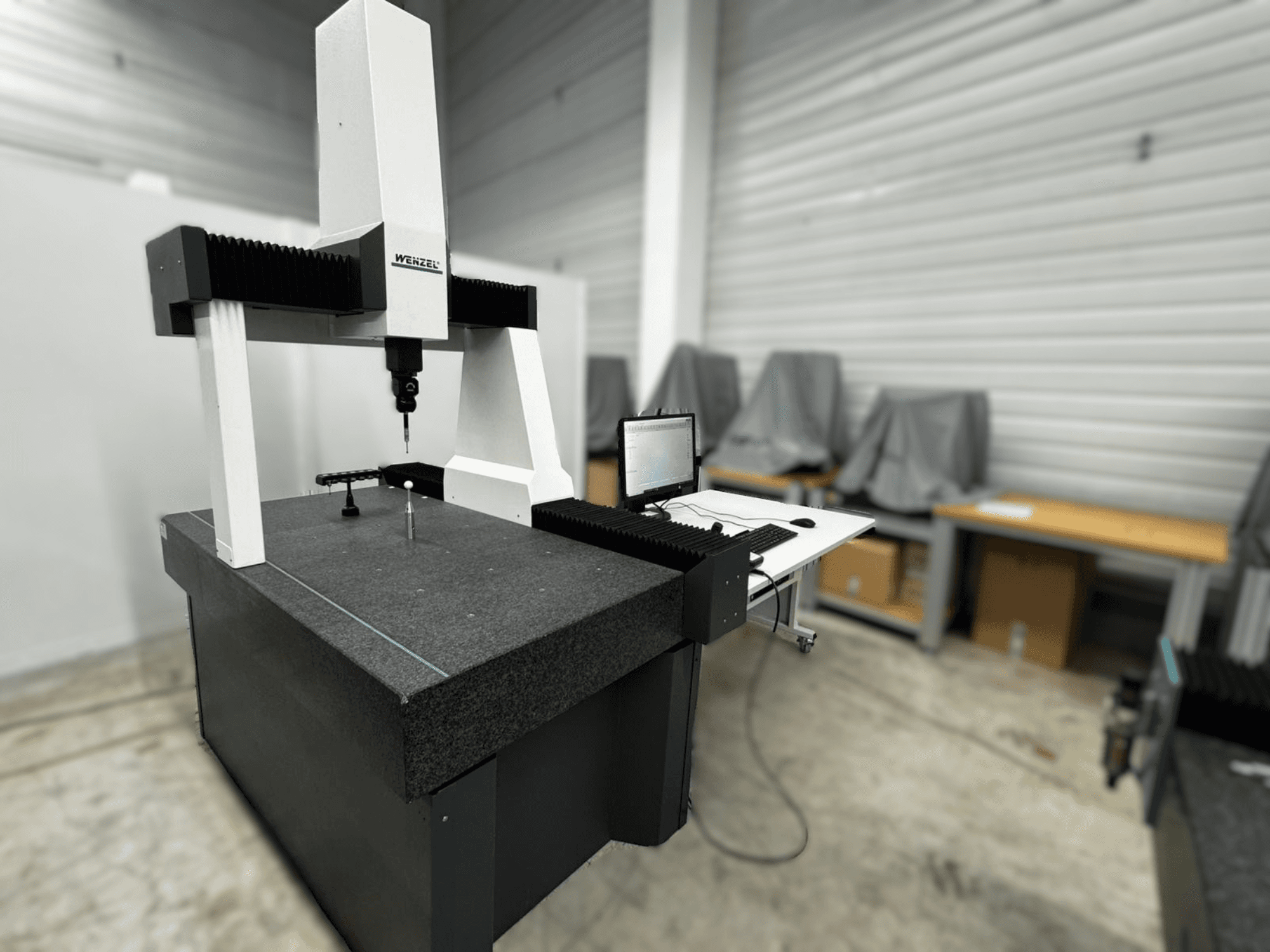 Koordinatni mjerni stroj Wenzel LH 54 u bočnom prikazu, s mjernom sondom i računalnim sučeljem na sivoj podlozi.