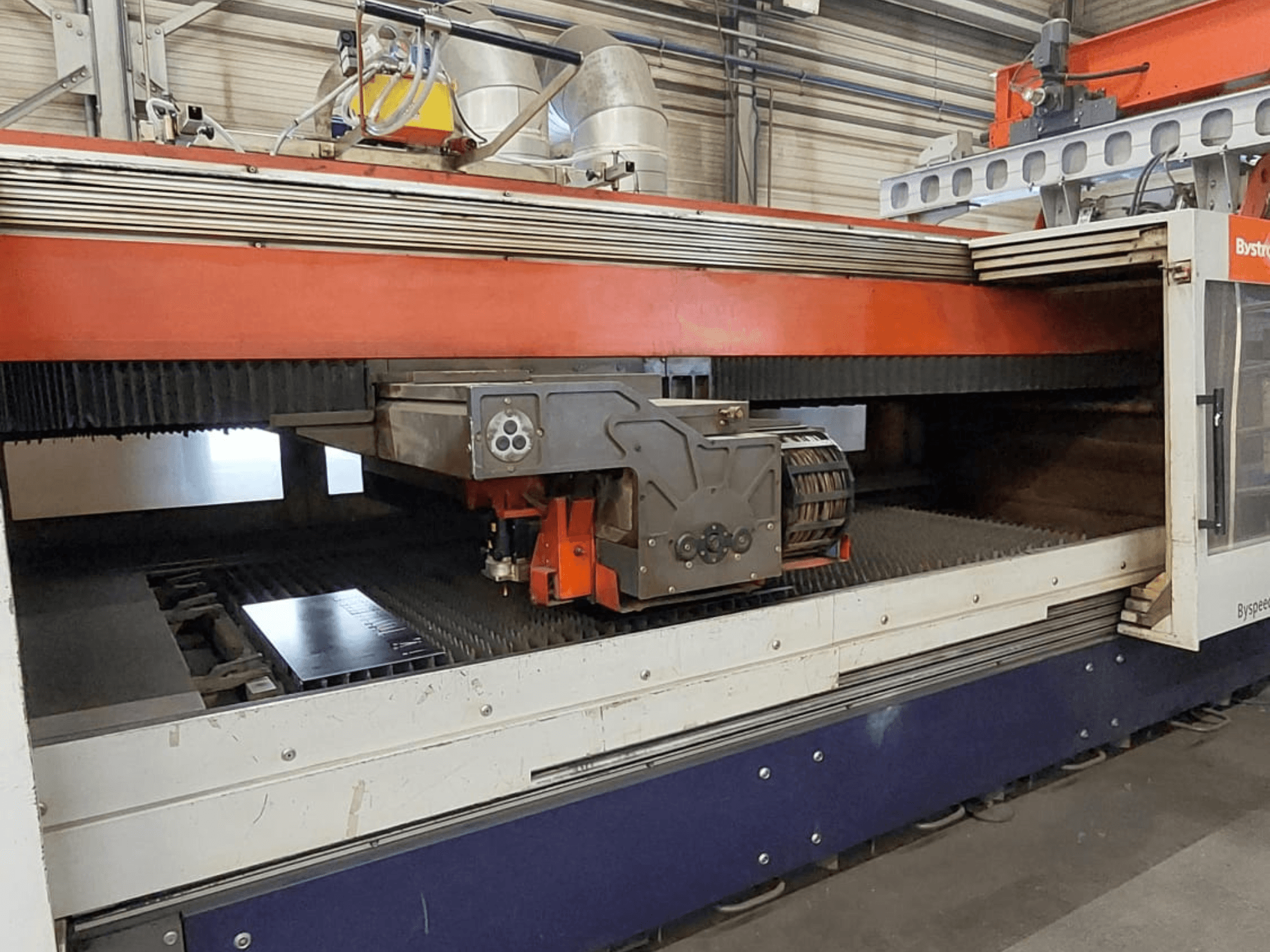 Stroj za rezanje CO2 laserom Bystronic BySpeed 3015, prednji pogled koji prikazuje glavu za rezanje i metalni lim na površini za rezanje.