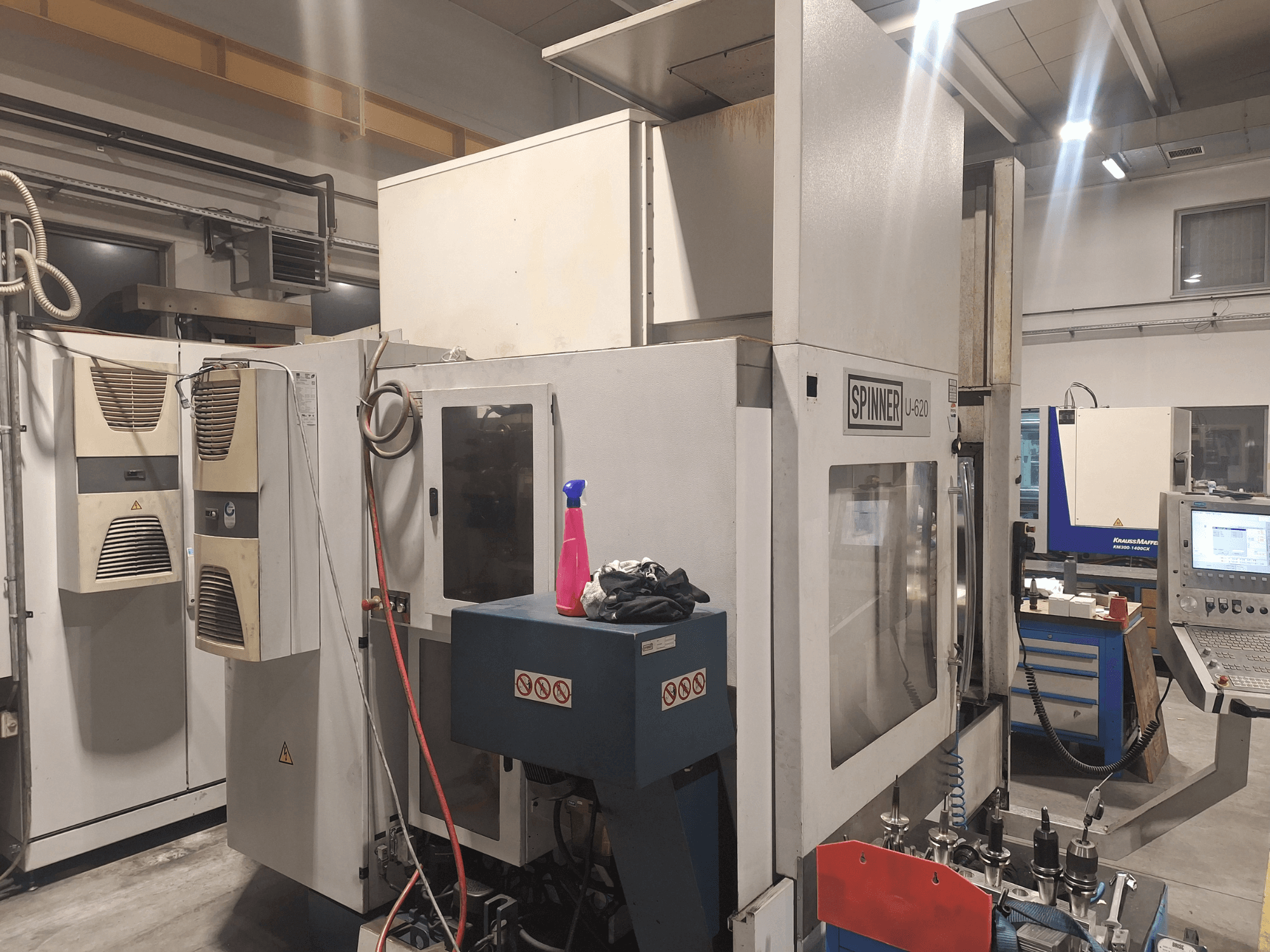 CNC stroj Spinner U-620 prikazan s prednje strane u radionici, s upravljačkom pločom i raznim alatima na obližnjem radnom stolu.