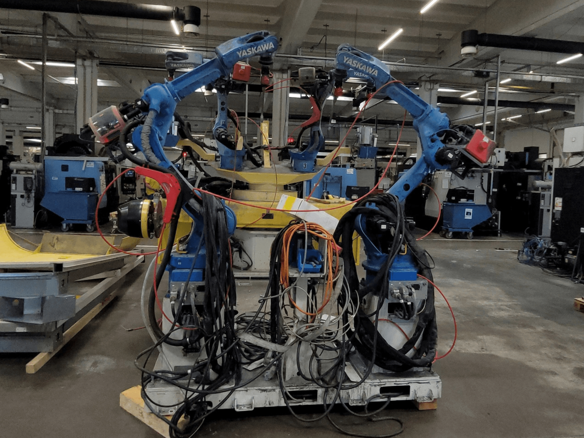 Yaskawa robotska ćelija za zavarivanje RWC L1_OS 15330, prednji pogled, s dva plava robota s opsežnim kabelima i alatima za zavarivanje.