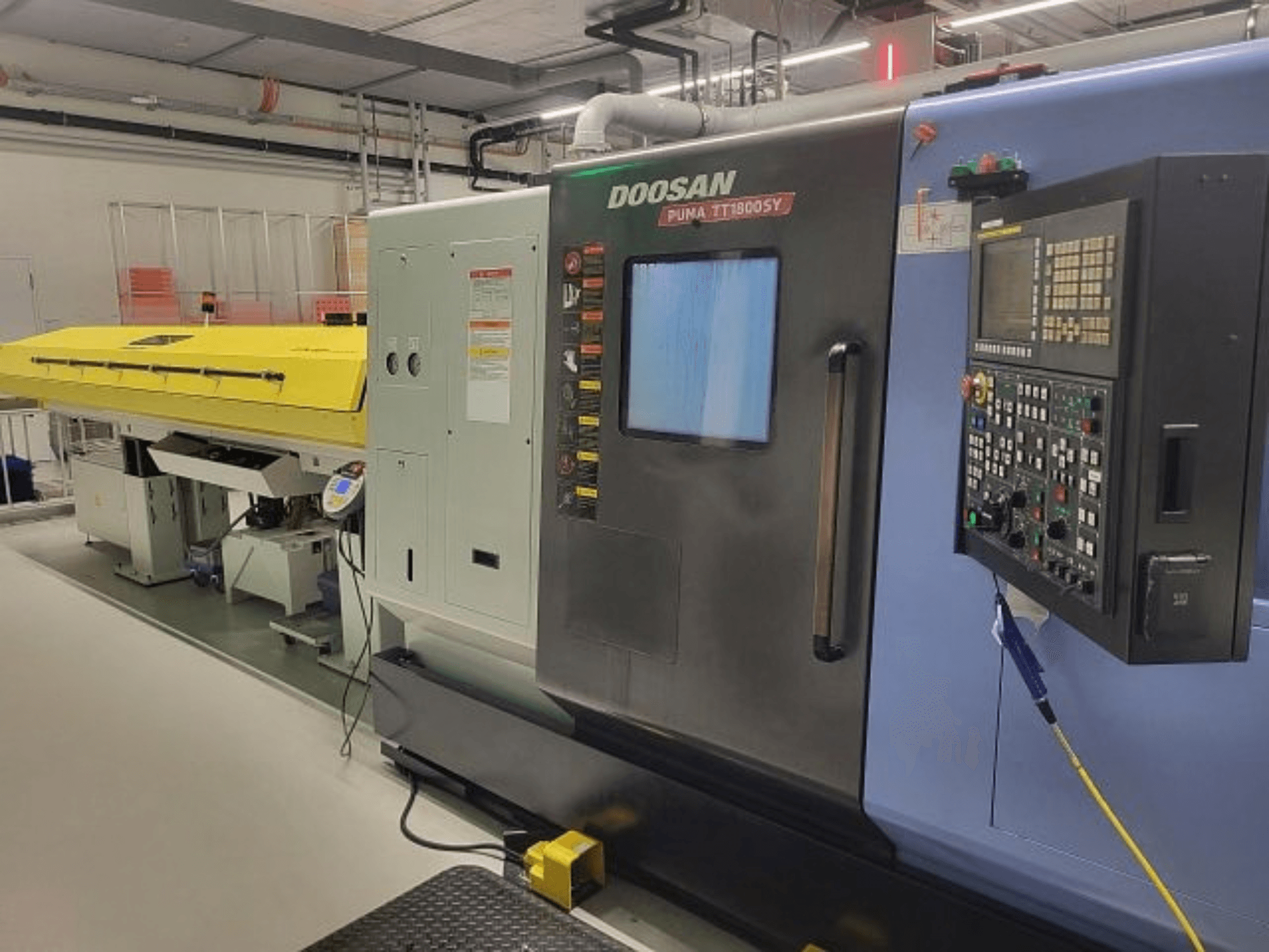 DOOSAN PUMA TT 1800 SY tokarsko-glodački centar, prednji pogled s upravljačkom pločom i žutim poklopcem, industrijsko okruženje.