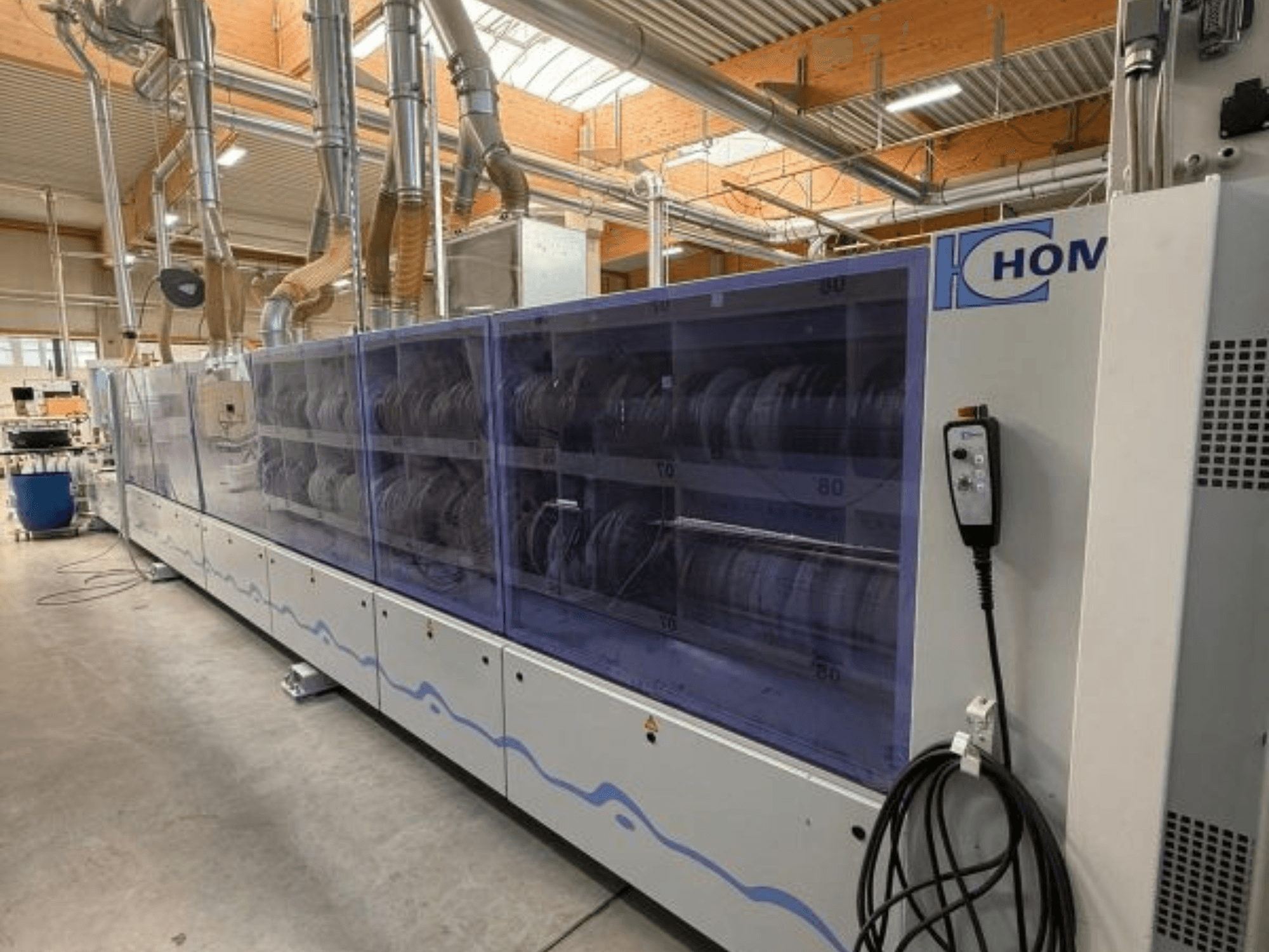 Industrijska perilica rublja HOM, prednji pogled, s prozirnom pločom na kojoj se vidi posuđe; upravljačka ploča s gumbima sa strane.