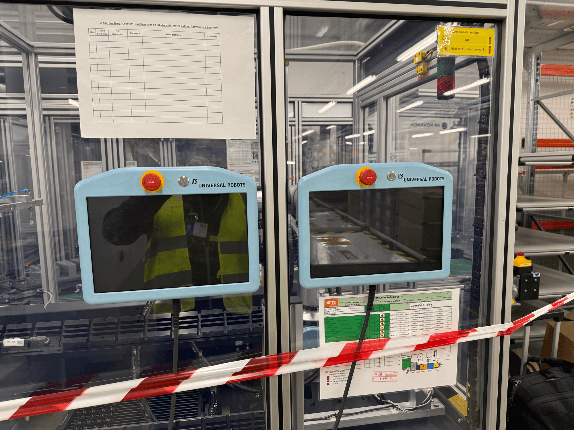Upravljačka ploča za robotsku ruku Universal Robots UR5 e, s dva monitora, tipkama za zaustavljanje u nuždi i sigurnosnim uputama.