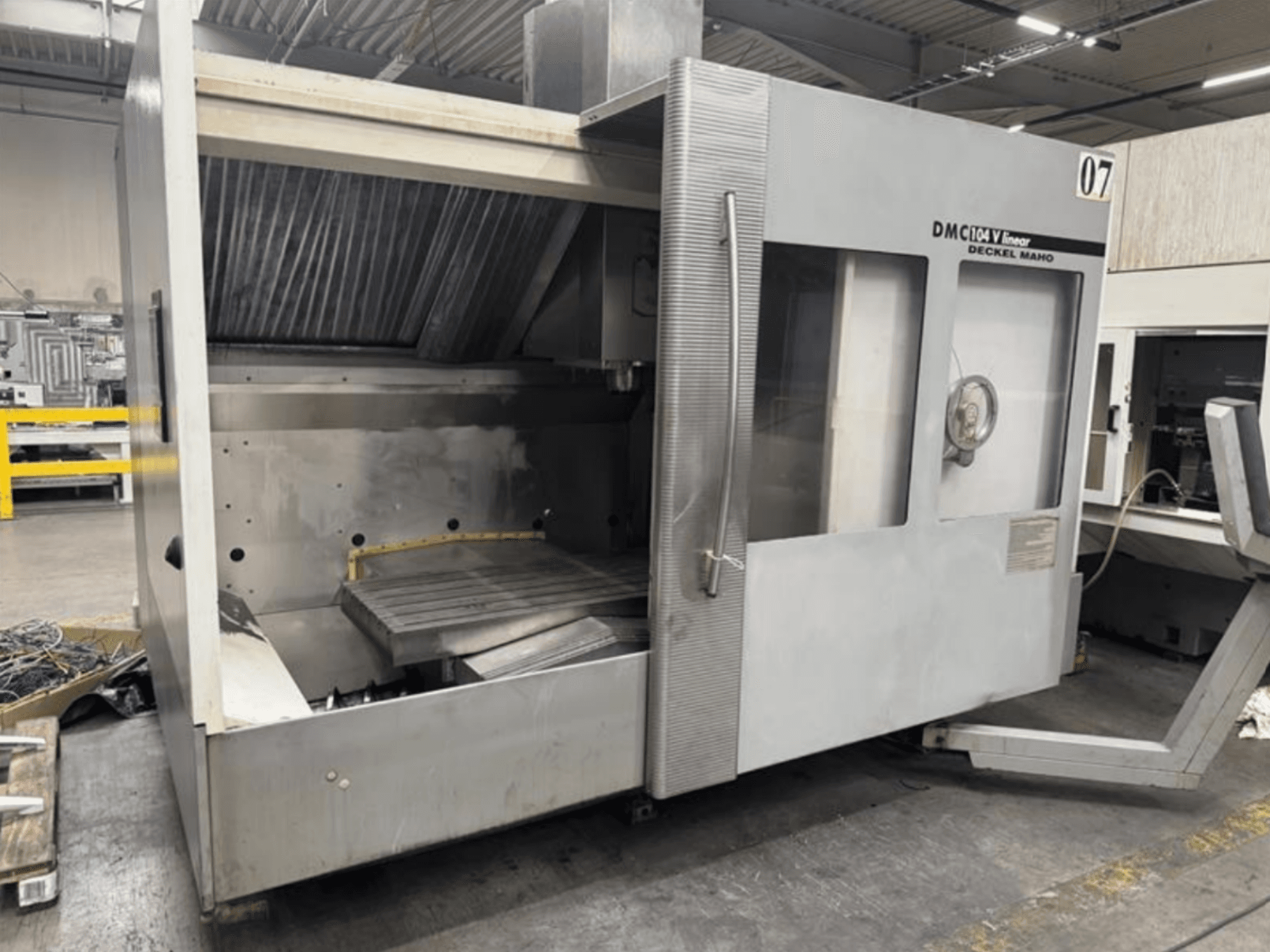 Linearni stroj DMC 104 V tvrtke Deckel Maho, prednji pogled, s praznim prostorom za obradu i velikim radnim stolom.