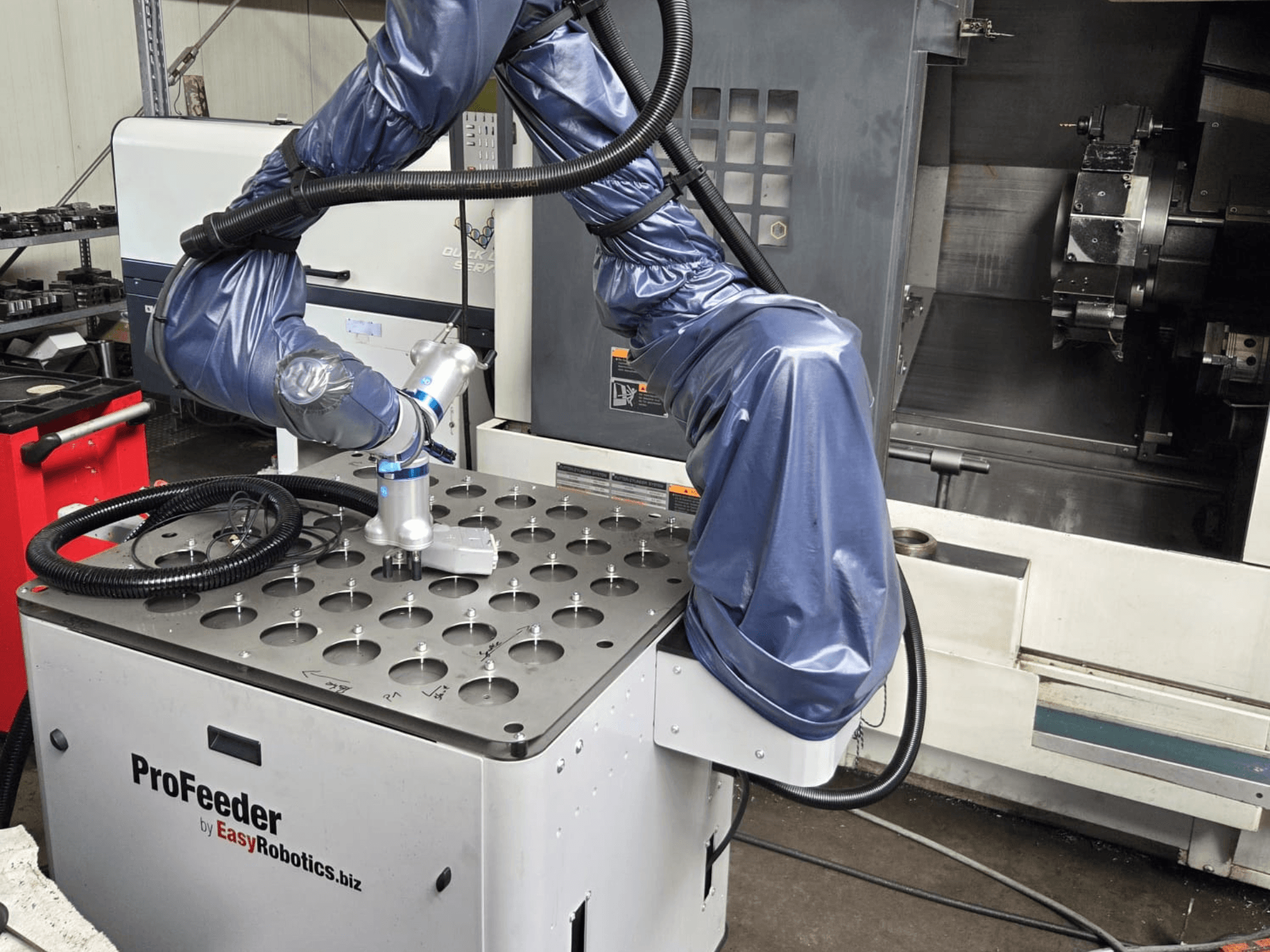 Kolaborativni robot EASYROBOTICS ProFeeder iz prednjeg pogleda, s robotskom rukom postavljenom iznad perforiranog metalnog stola.