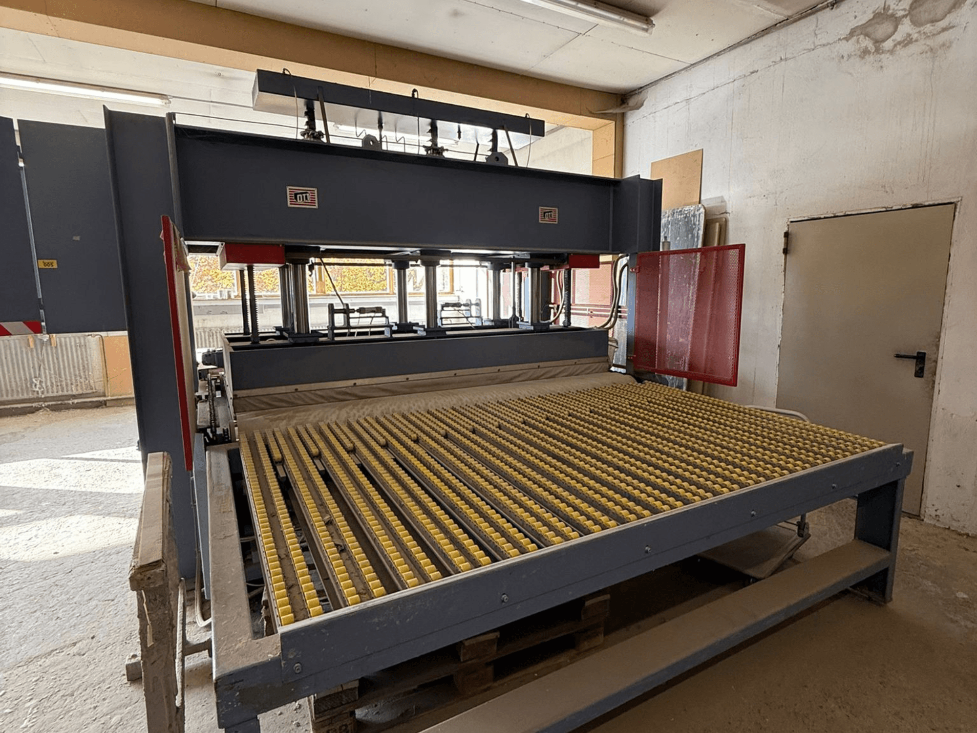 Industrijski stroj sa žutim valjcima, prednji pogled, vidljiv logotip marke, koristi se za obradu materijala u radionici.