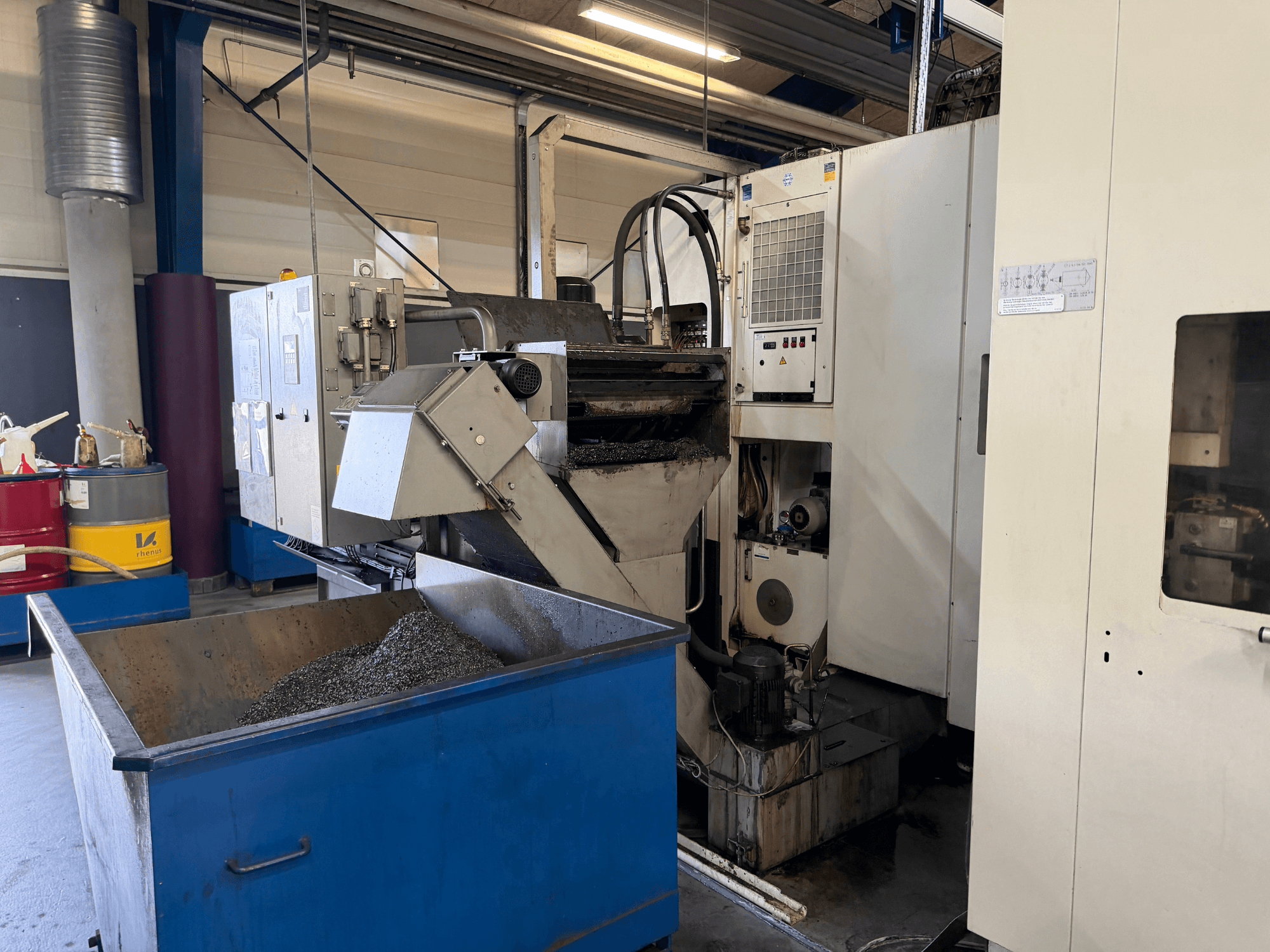 Prednji pogled na horizontalni obradni centar HELLER MCH 250 s vidljivom posudom za recikliranje metalne rashladne tekućine i upravljačkom pločom.