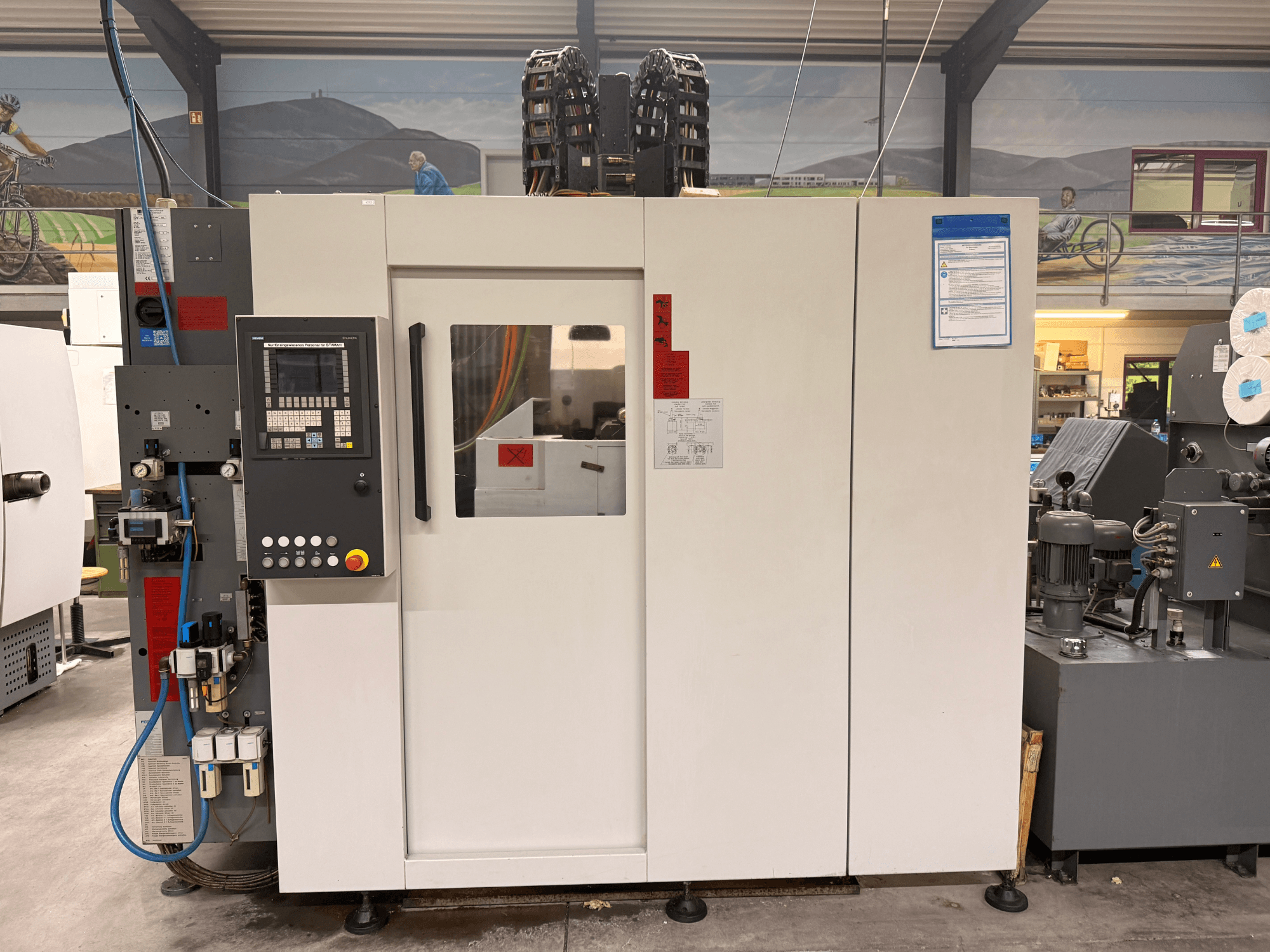 Bijeli CNC obradni centar s upravljačkom pločom, prednji pogled, s gumbima i digitalnim zaslonom, u radioničkom okruženju.