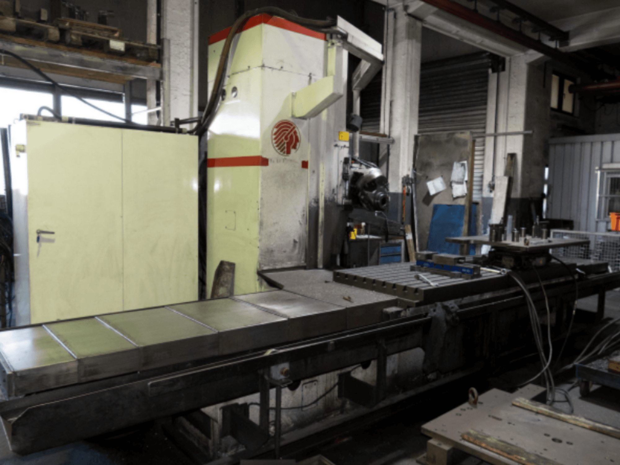 Industrijska glodalica s velikim stolom, bočni pogled, s prikazom kontrola i dodataka u radioničkom okruženju.