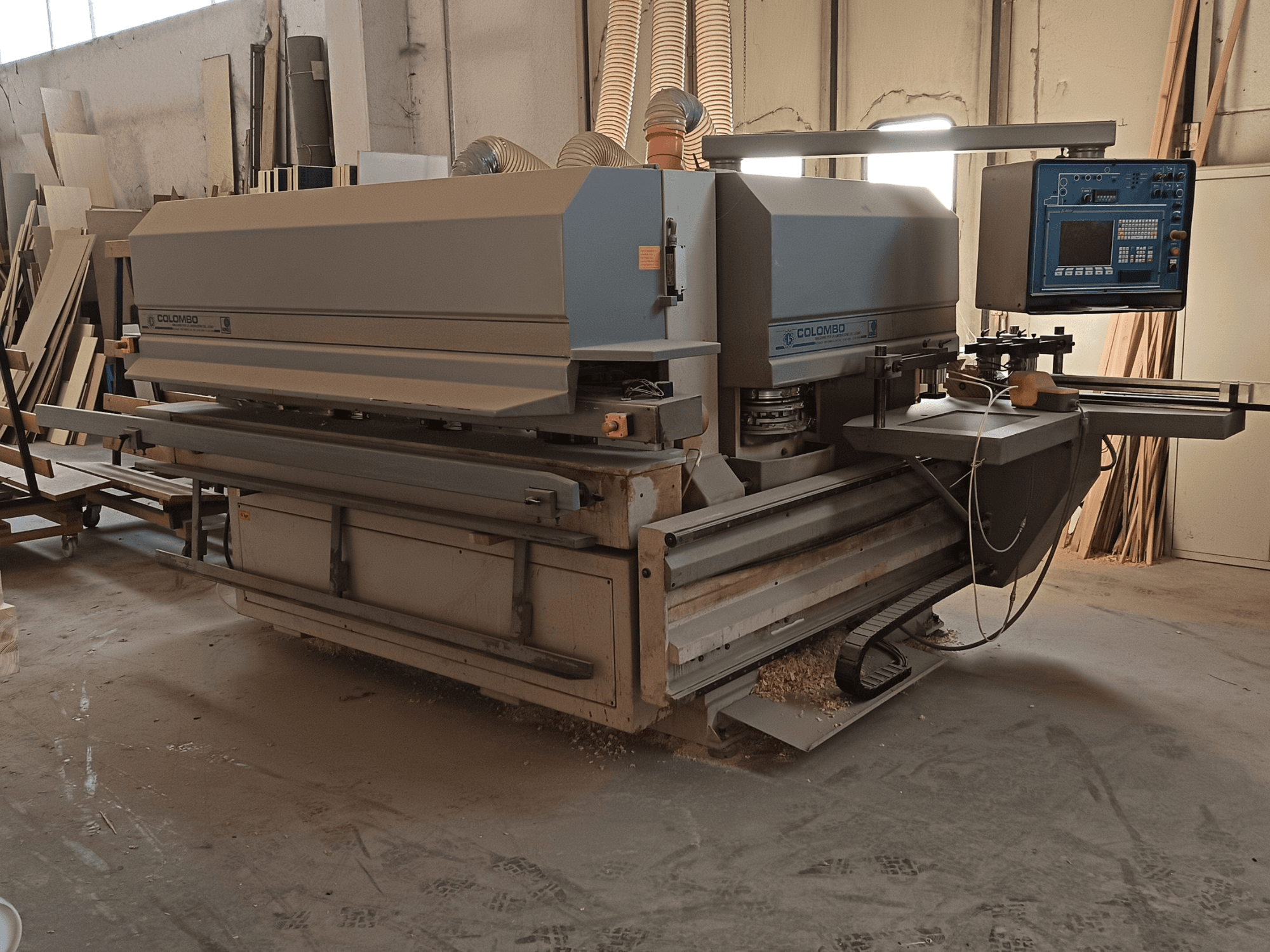 Stroj za obradu drveta Colombo, bočni pogled, prikaz upravljačke ploče, oštrica za rezanje i nakupine piljevine u radionici.