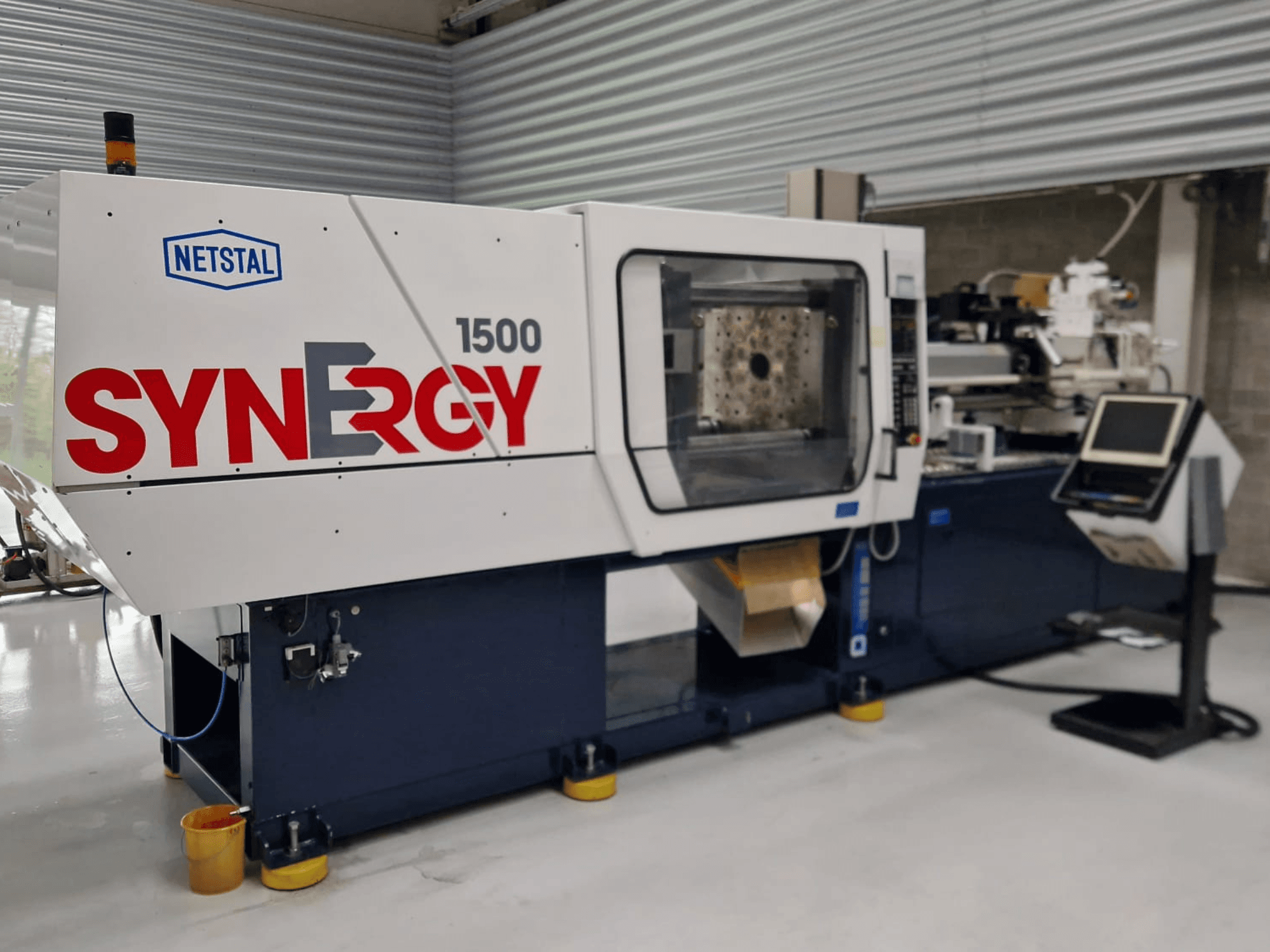 Netstal Synergy 1500-460 hidraulični stroj za brizganje plastike, prednji pogled, s prikazom upravljačke ploče i otvorenog prostora za brizganje.