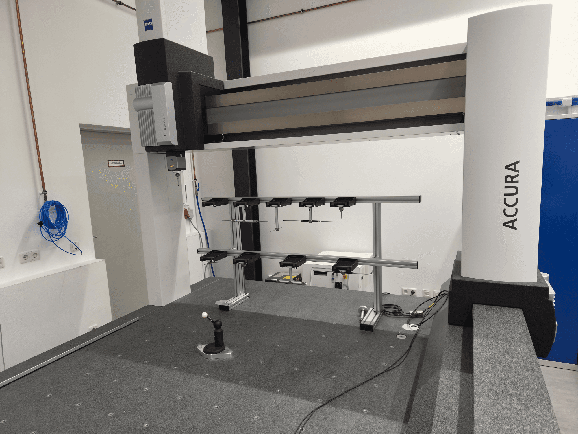ZEISS ACCURA 16/24/10 CMM u prednjem pogledu, s prikazom mjerne ruke, baze i upravljačkog sučelja na sivoj površini prekrivenoj tepihom.