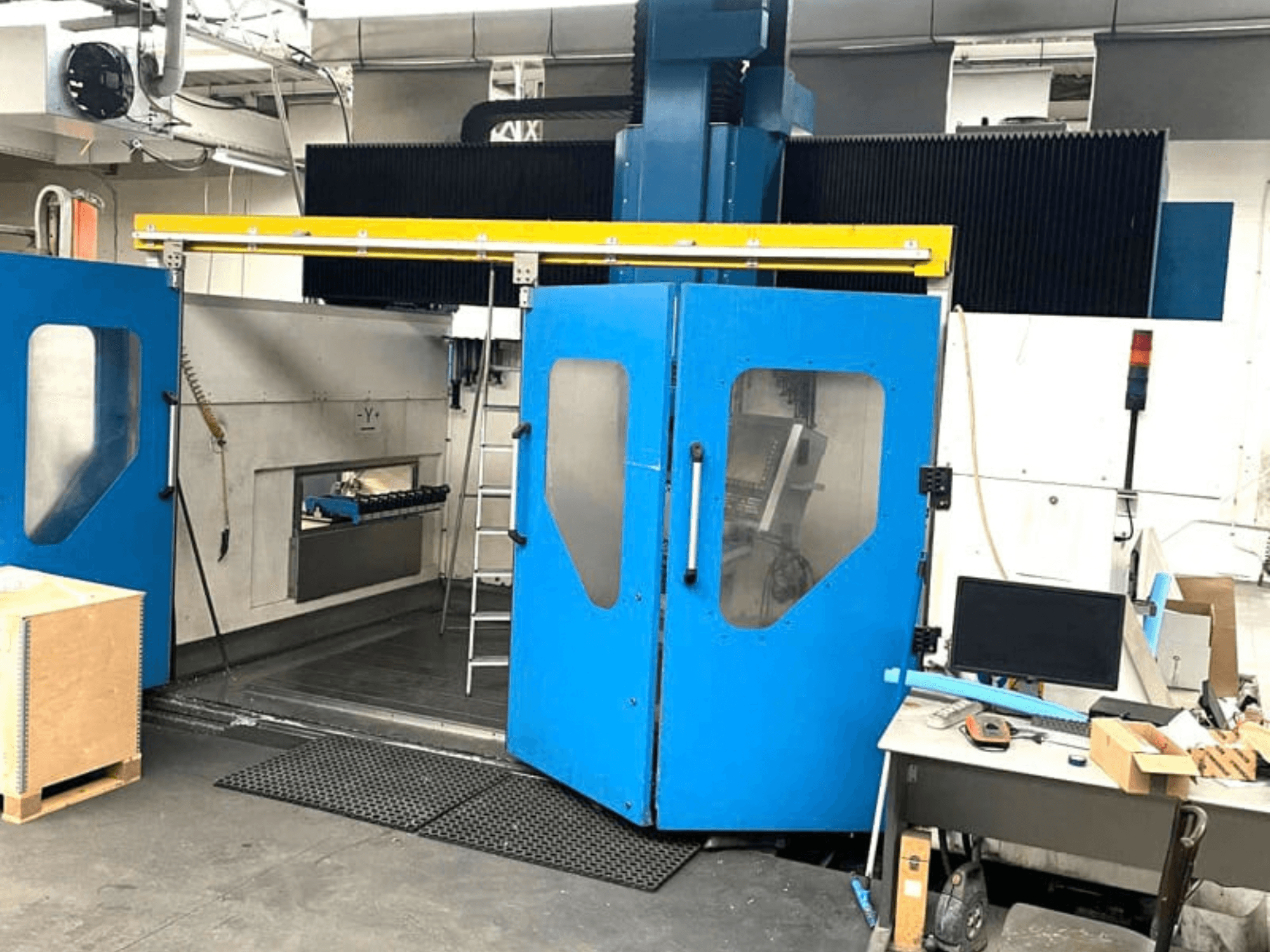 Prednji pogled na vertikalni obradni centar TECHMILL LABOR SHAPE 3220 s otvorenim plavim vratima, otkrivajući radni prostor unutra.