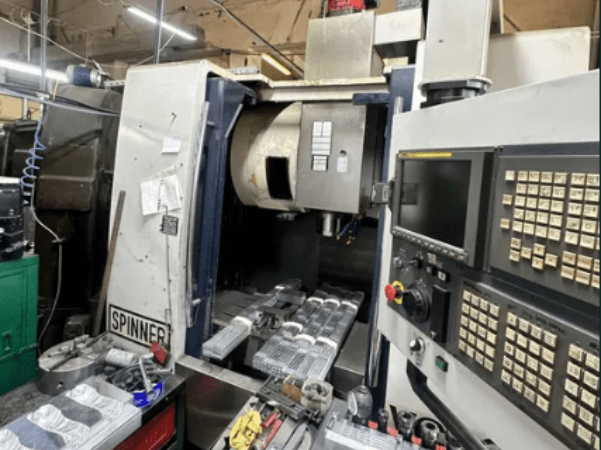 CNC stroj tvrtke Spinner, prednji pogled; ima sučelje osjetljivo na dodir, alate na radnom prostoru i obrađene dijelove spremne za obradu.