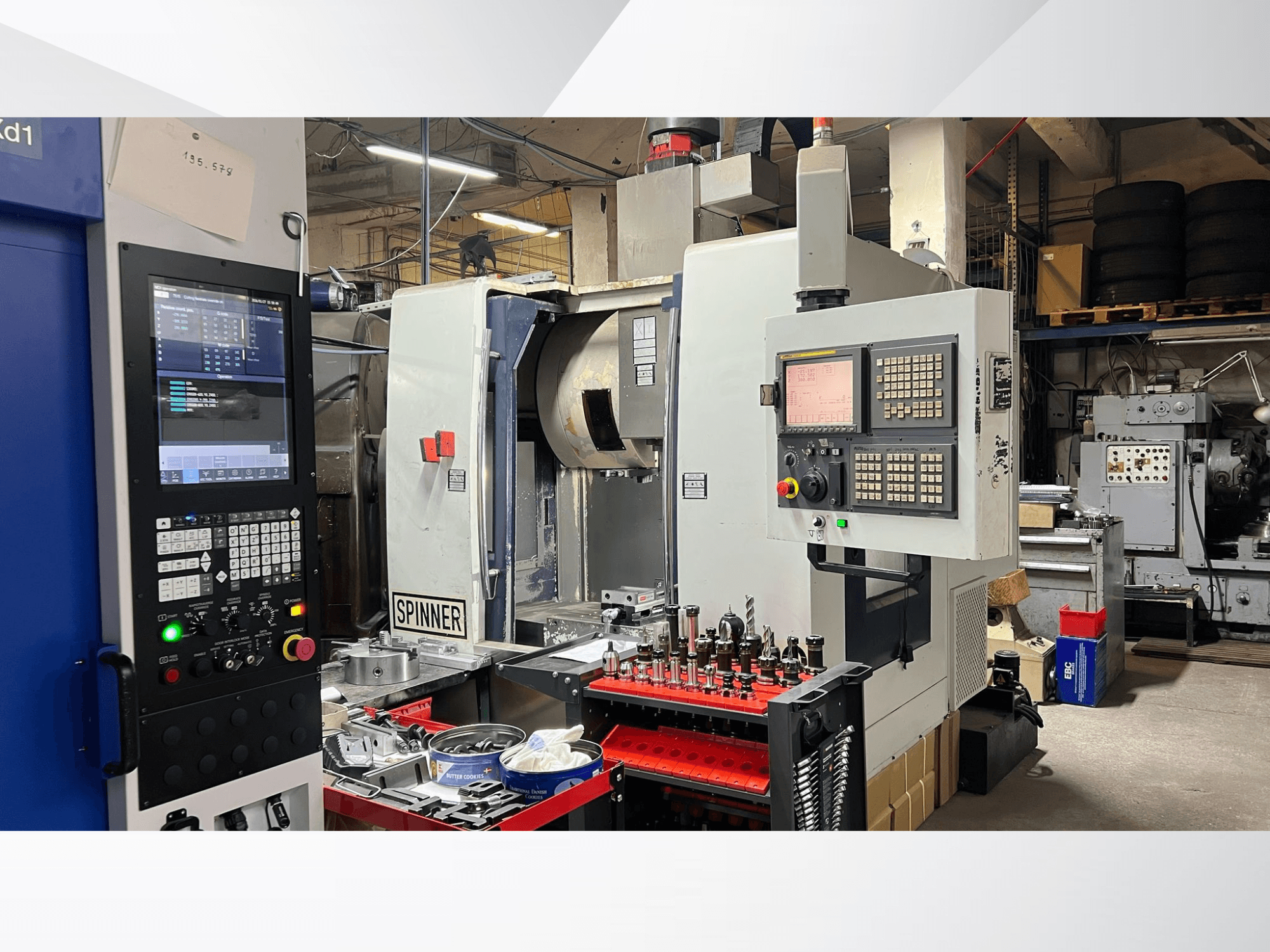 CNC stroj s vidljivom upravljačkom pločom, alatima i radnim komadima, gledano iz prednjeg kuta u radioničkom okruženju.