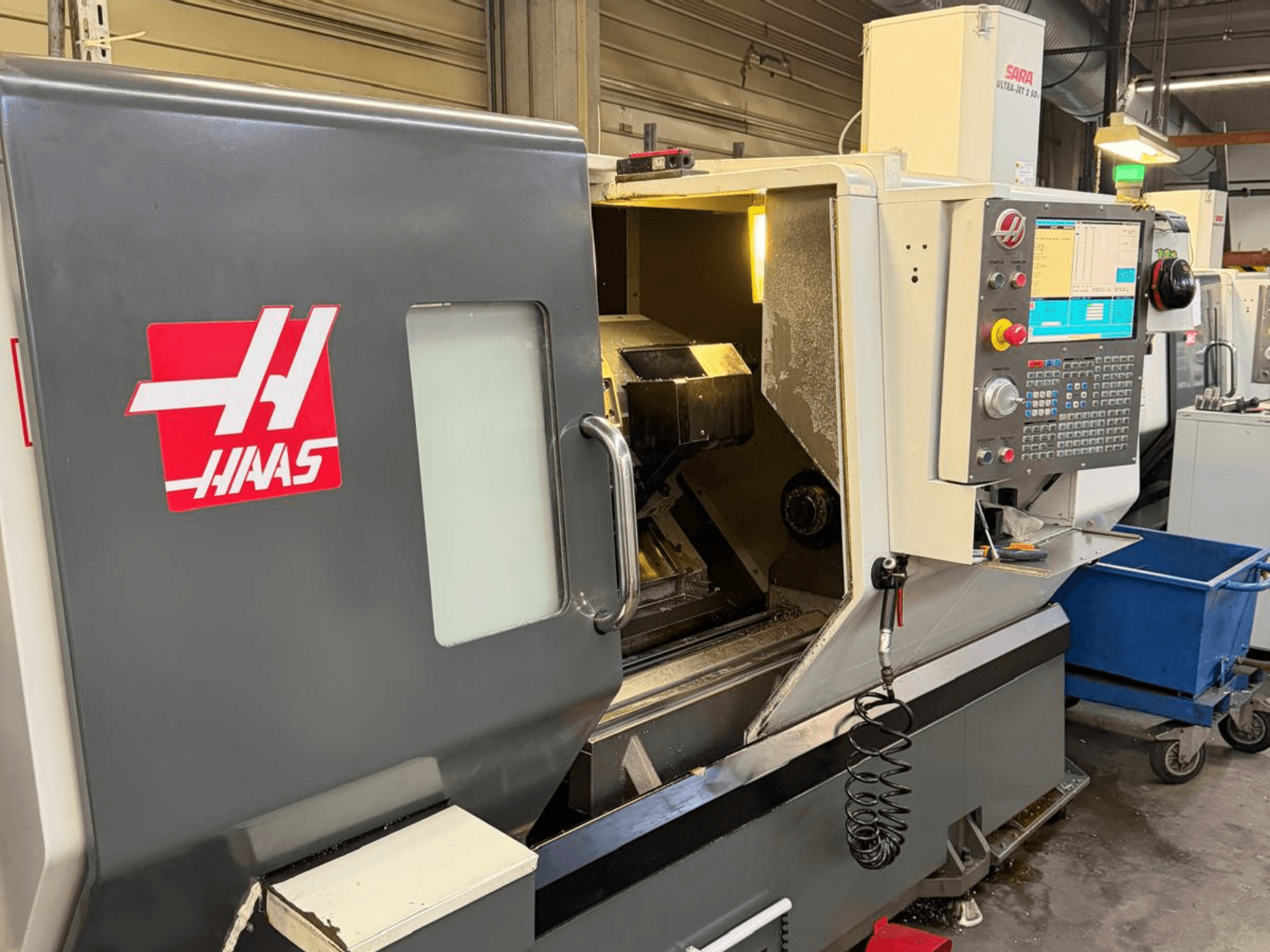 HAAS DS-30SSY horizontalni tokarski stroj, pogled sprijeda, s vidljivom upravljačkom pločom i unutarnjim komponentama, u radioničkom okruženju.