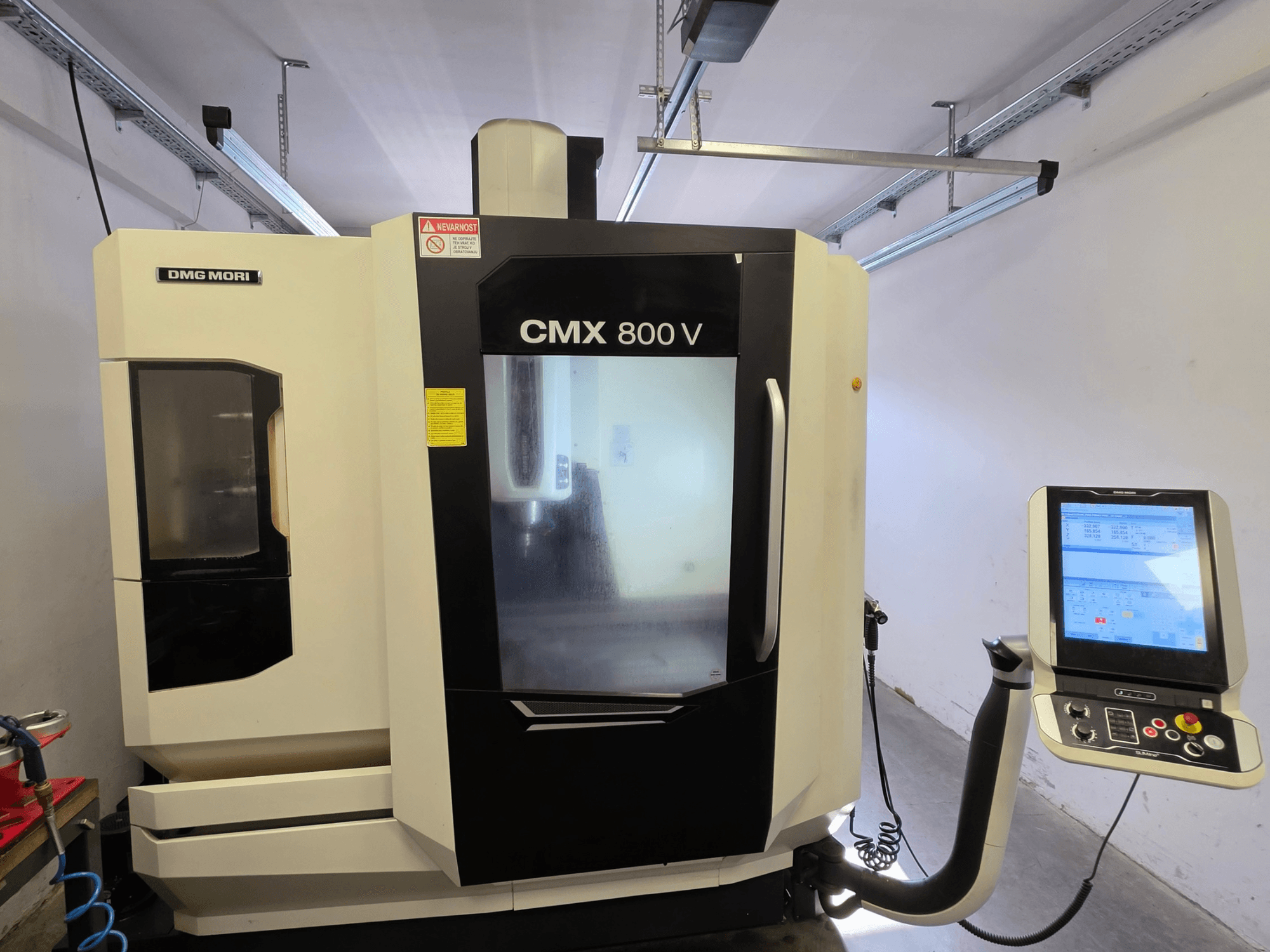 Vertikalni obradni centar DMG MORI CMX 800V, prednji pogled, s upravljačkom pločom s dodirnim zaslonom i jasnim sigurnosnim oznakama.