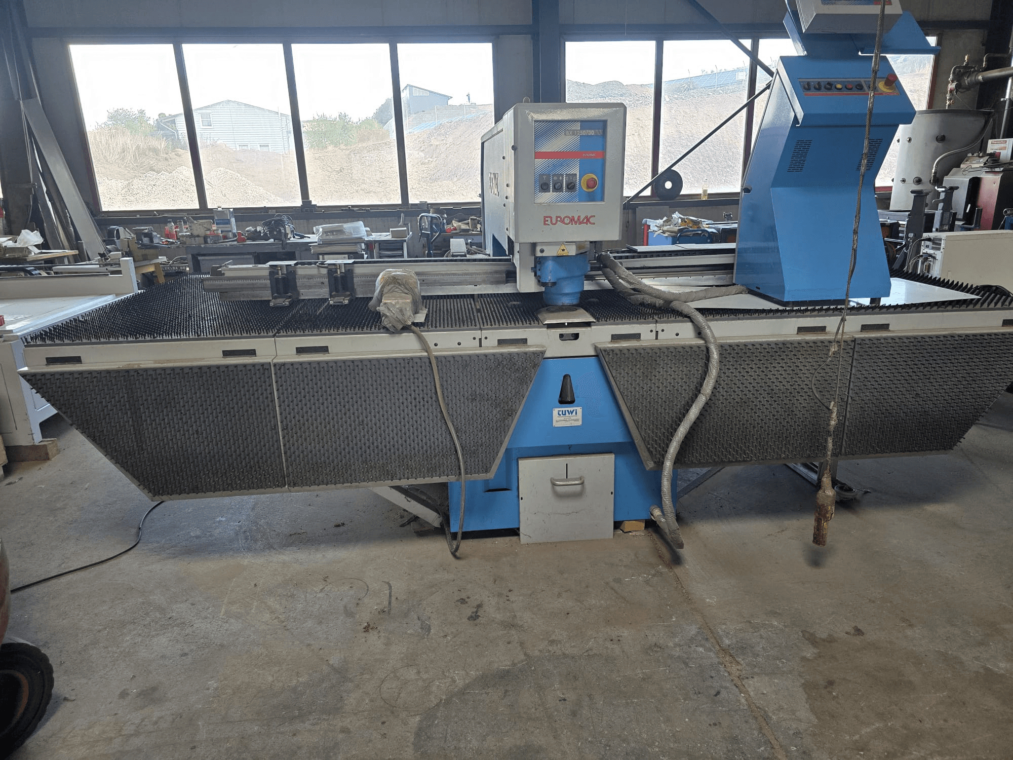 CNC stroj za probijanje Euromac BX 1250/30 u radionici, bočni pogled s prikazom kontrola alata, industrijskog dizajna i kreveta za rezanje metala.