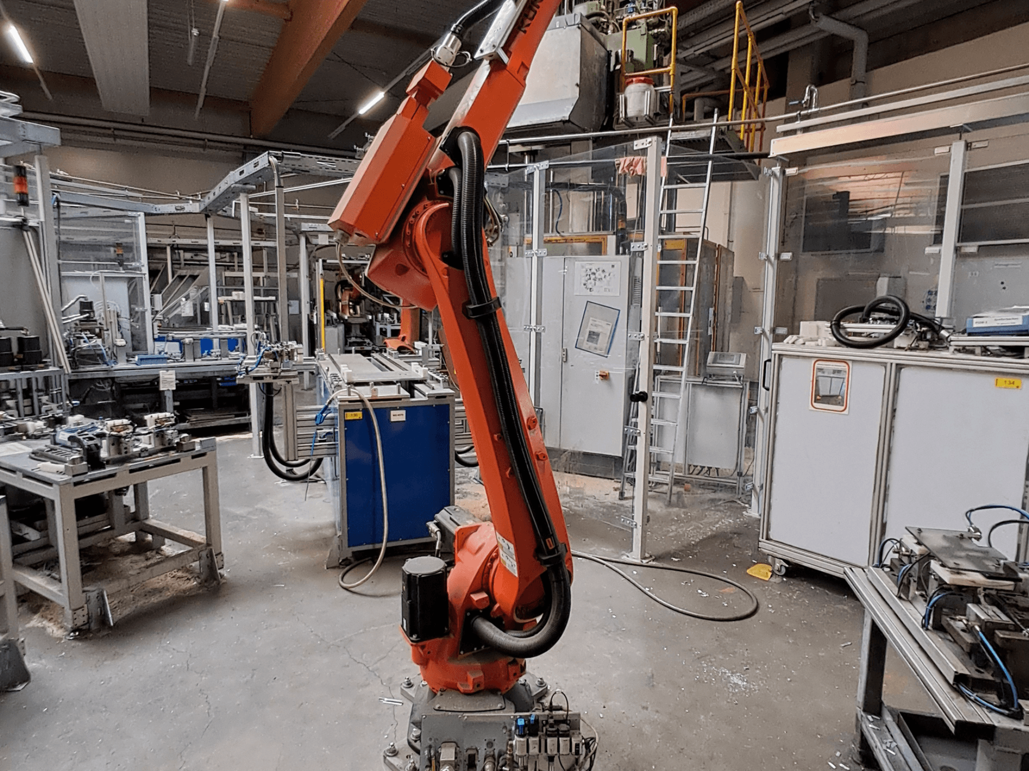 Robotska ruka KUKA KR 26 R3100/SEL u industrijskom okruženju, prikazana sa strane s operativnom opremom u pozadini.