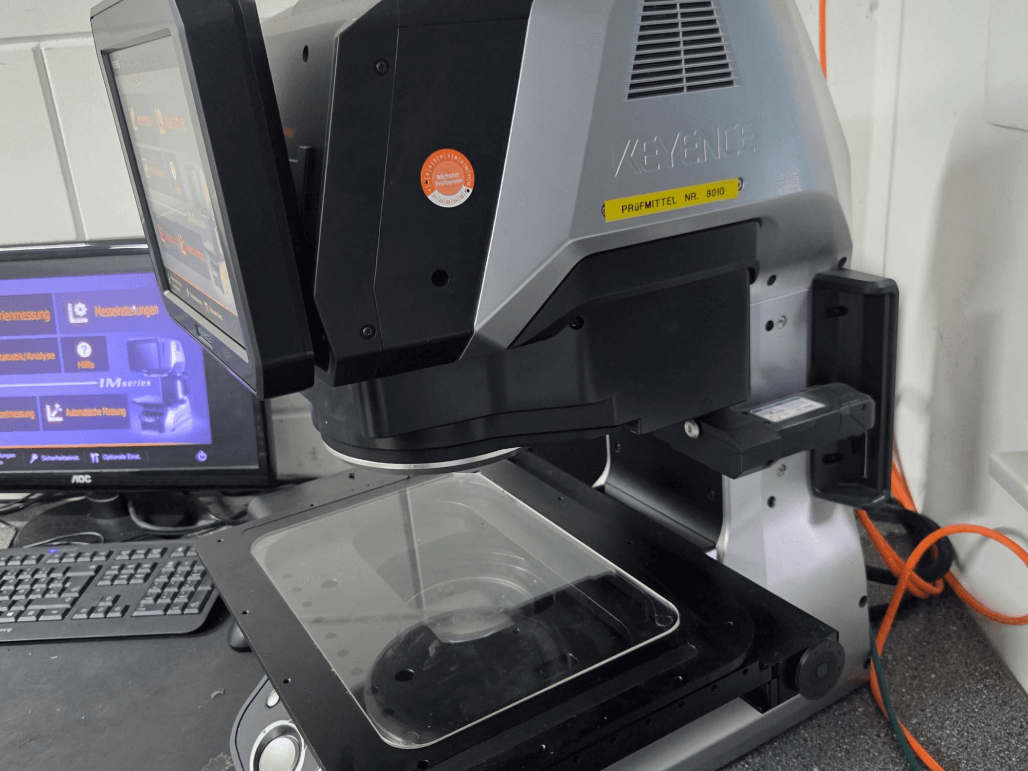 Optički mjerni stroj KEYENCE IM 7030, prednji pogled s dodirnim zaslonom i staklenom mjernom pločom.