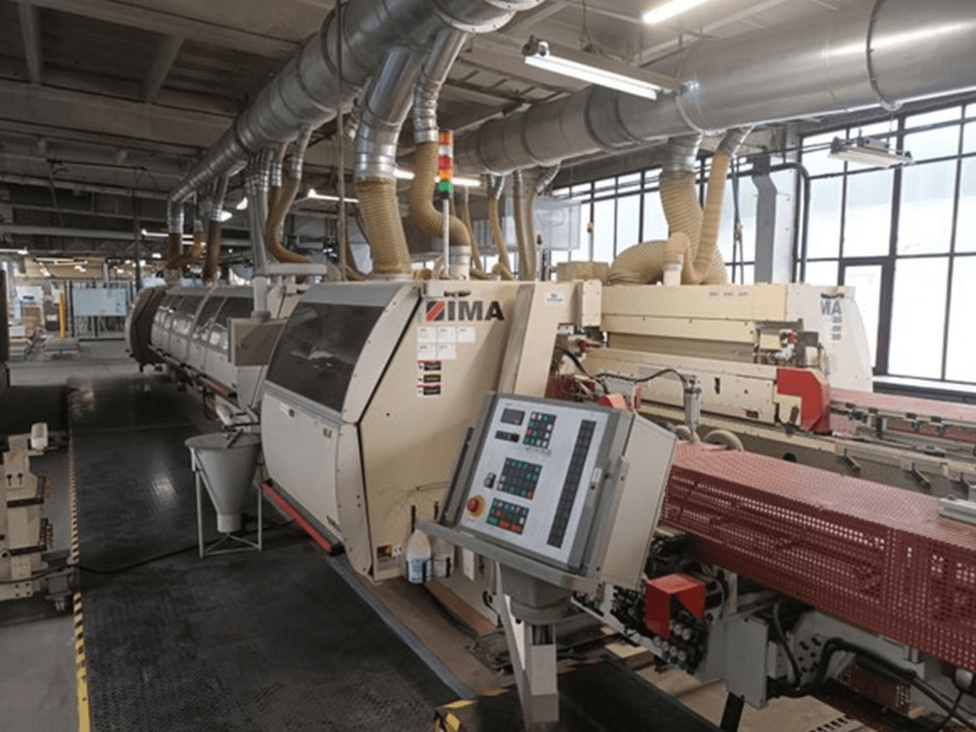 Industrijski strojevi IMA u tvorničkom okruženju, prednji pogled, s upravljačkim pločama i cijevima za usisavanje prašine.