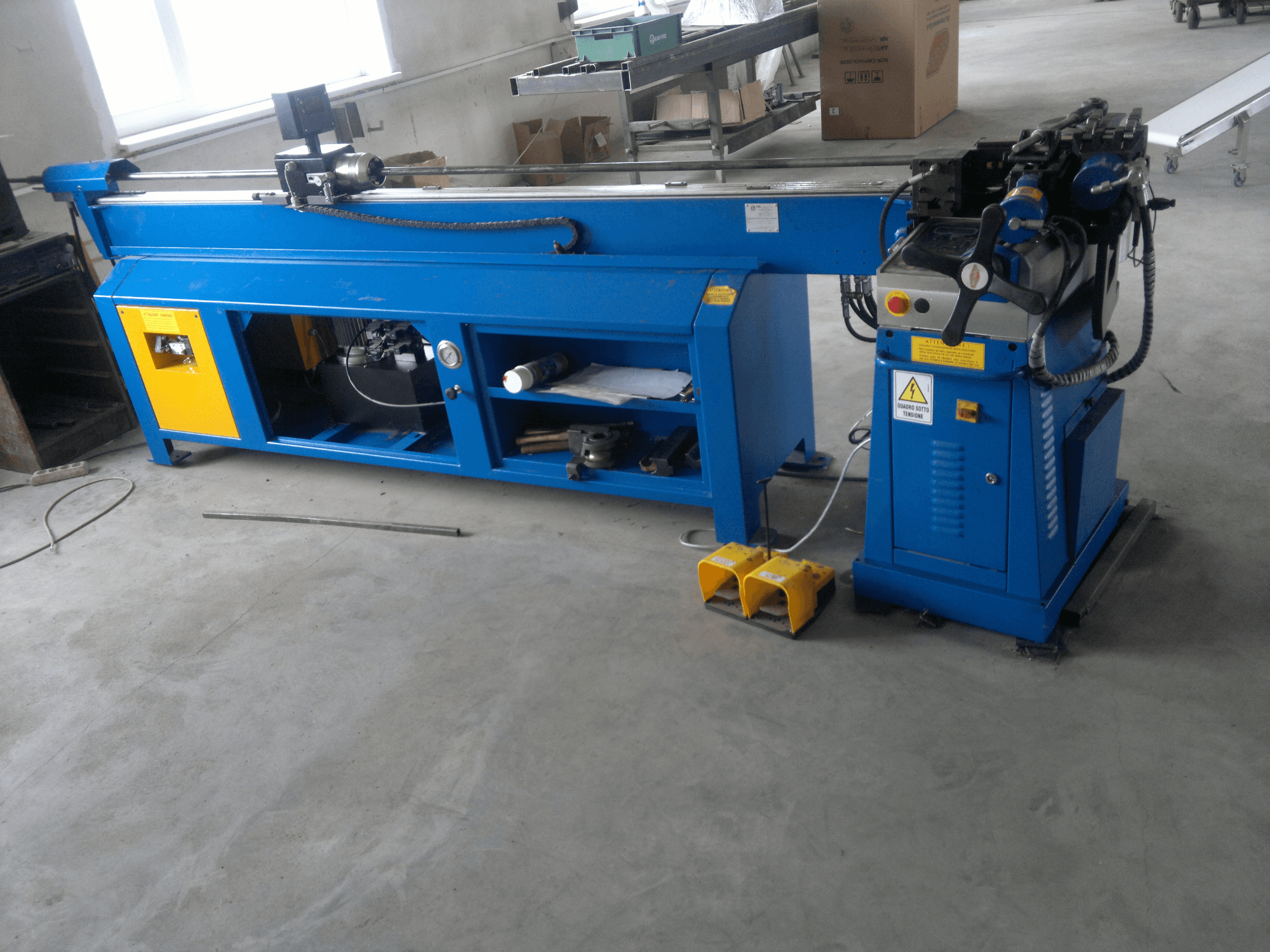 Plavi stroj za obradu drveta sa žutim detaljima, bočni pogled; ima upravljačku ploču, papučice i rotirajući sklop noževa.