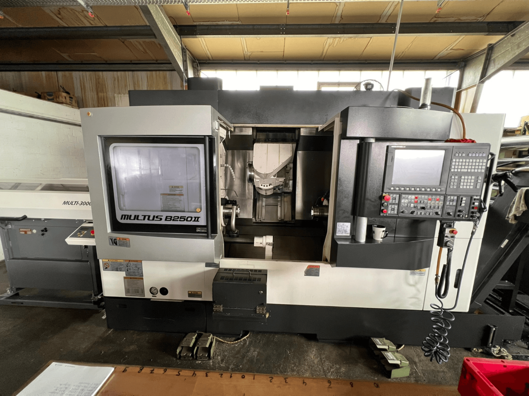 Okuma Multus B250II MW tokarsko-glodački centar, pogled sprijeda, prikaz upravljačke ploče i detalja područja obrade.