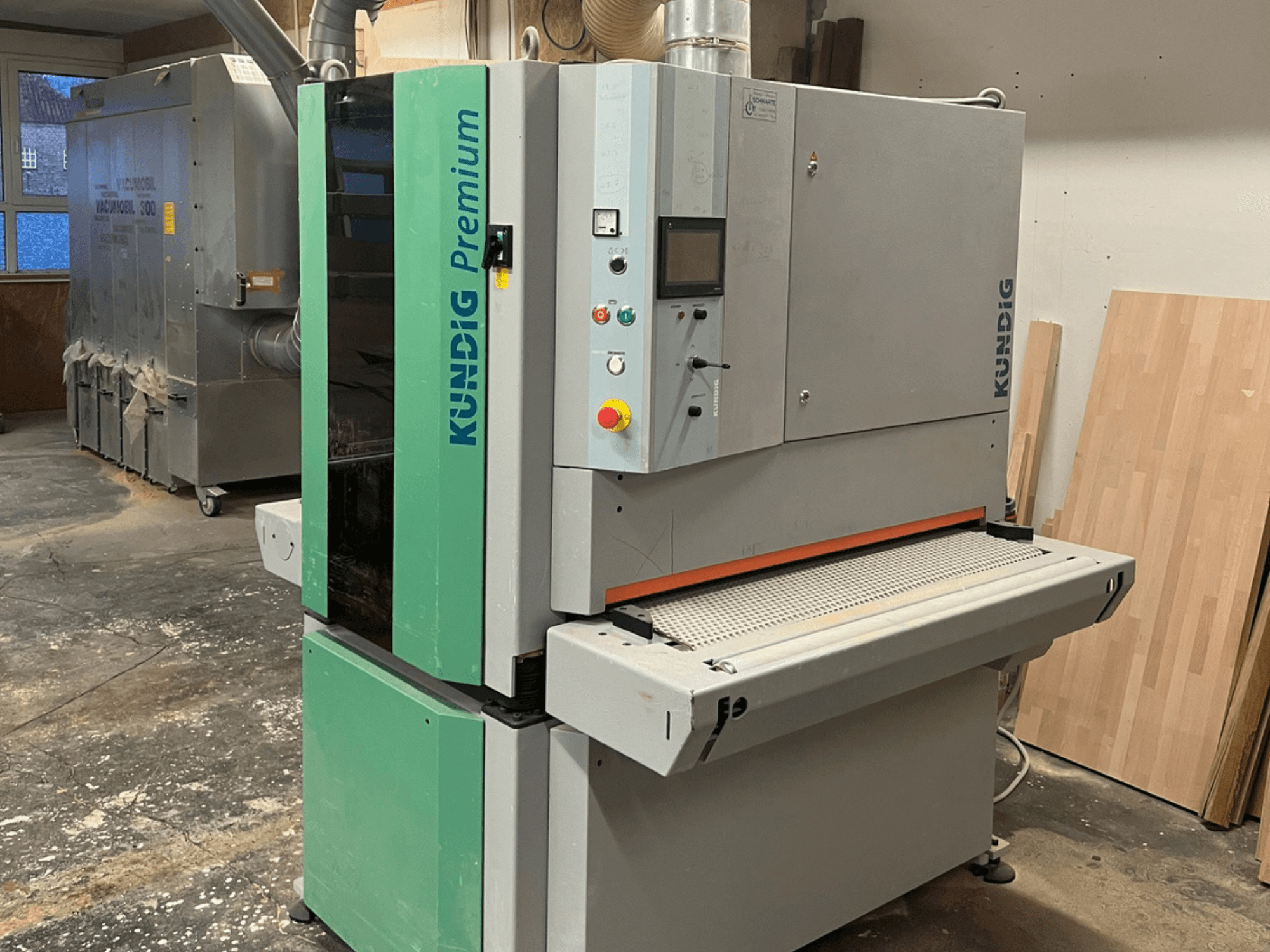 Tračna brusilica Kundig Premium-1 1100K u sivoj i zelenoj boji, prikazana u bočnom pogledu s vidljivom upravljačkom pločom i brusnom trakom.