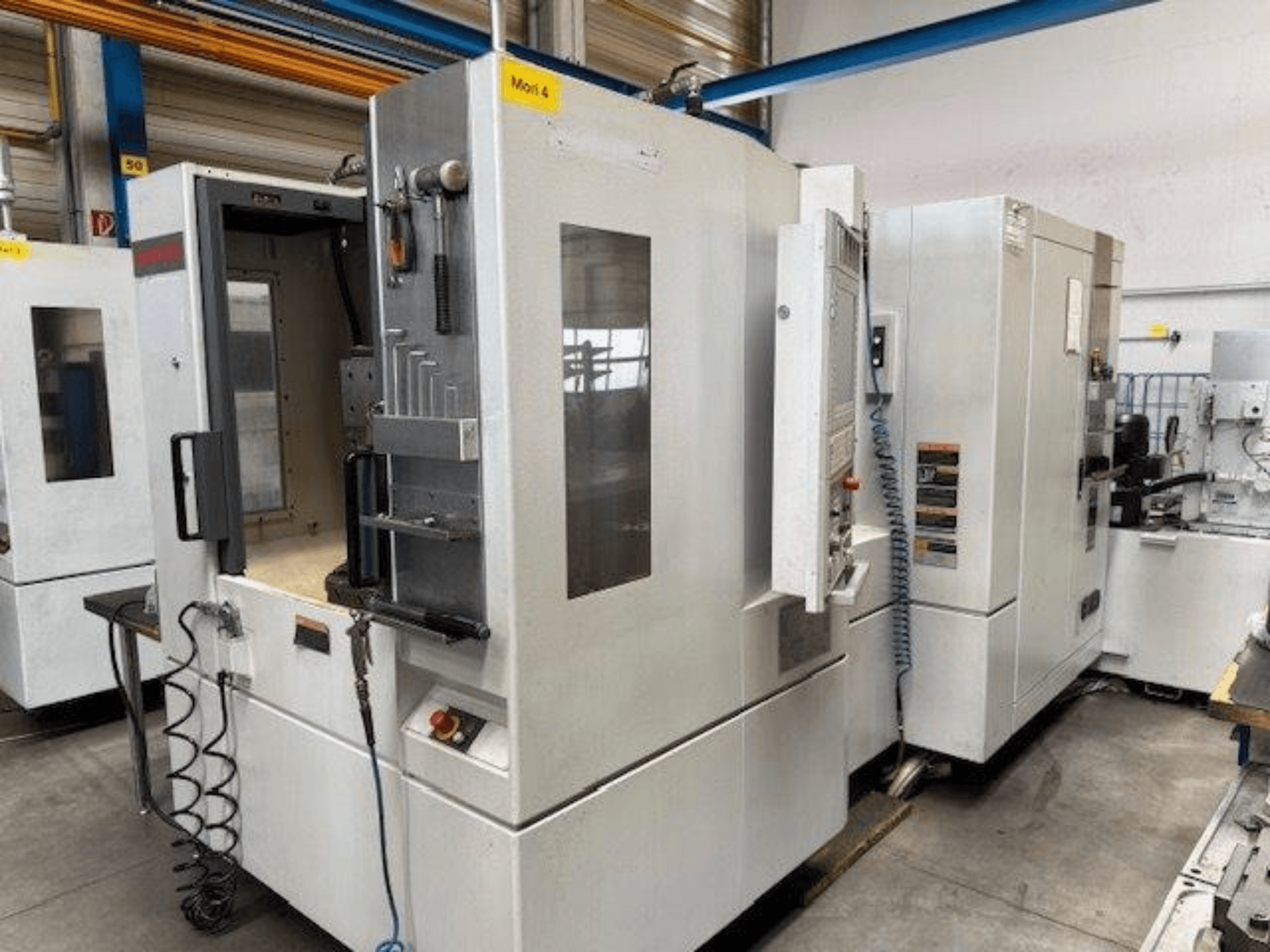 Horizontalni obradni centar MORI SEIKI NH4000 DCG prikazan s prednje strane, s otvorenim vratima i detaljima upravljačke ploče.
