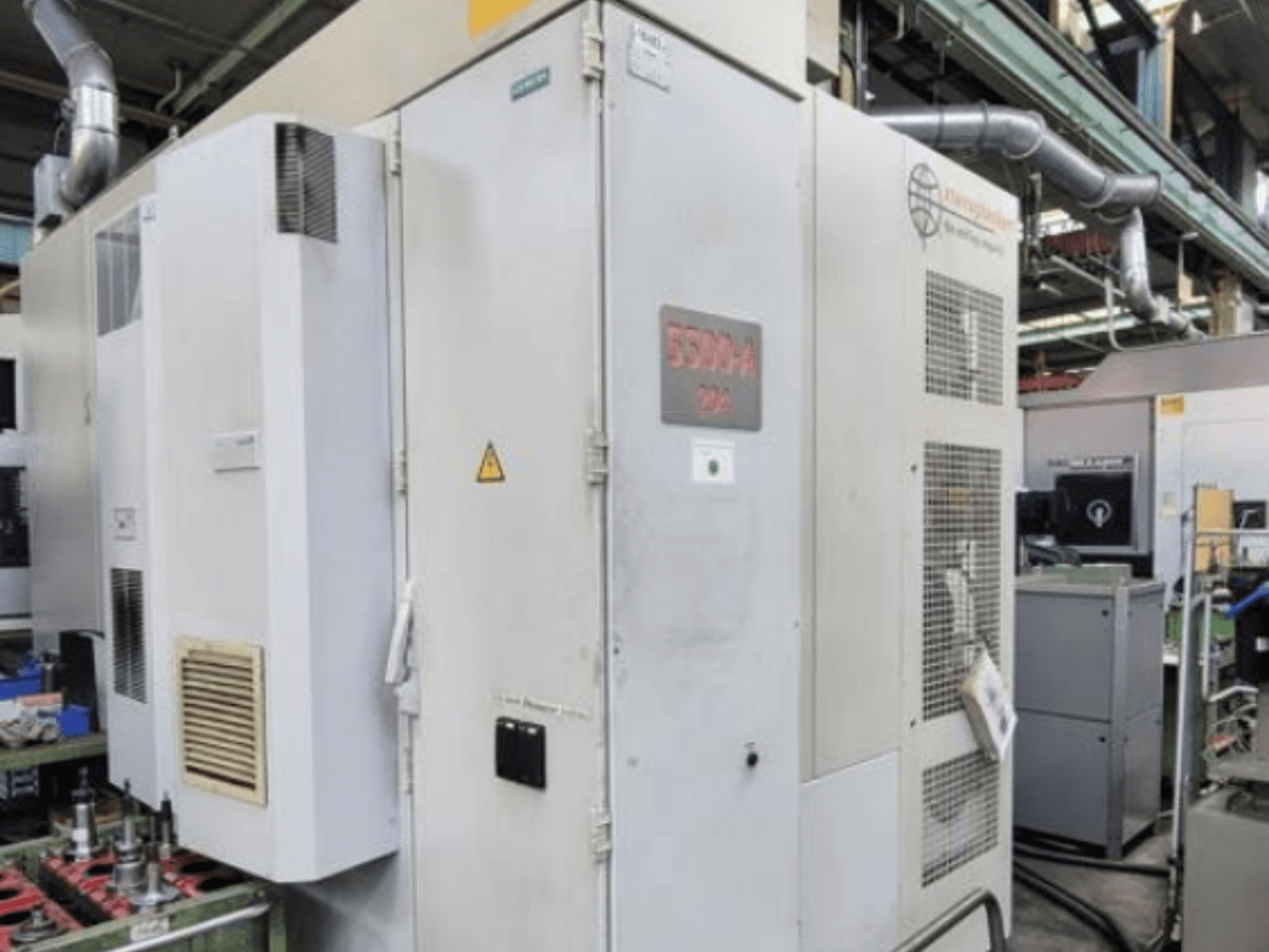 Horizontalni obradni centar Starrag Heckert HEC 500 H/V, bočni pogled koji prikazuje vanjski dio s otvorima za ventilaciju i znakovima upozorenja.