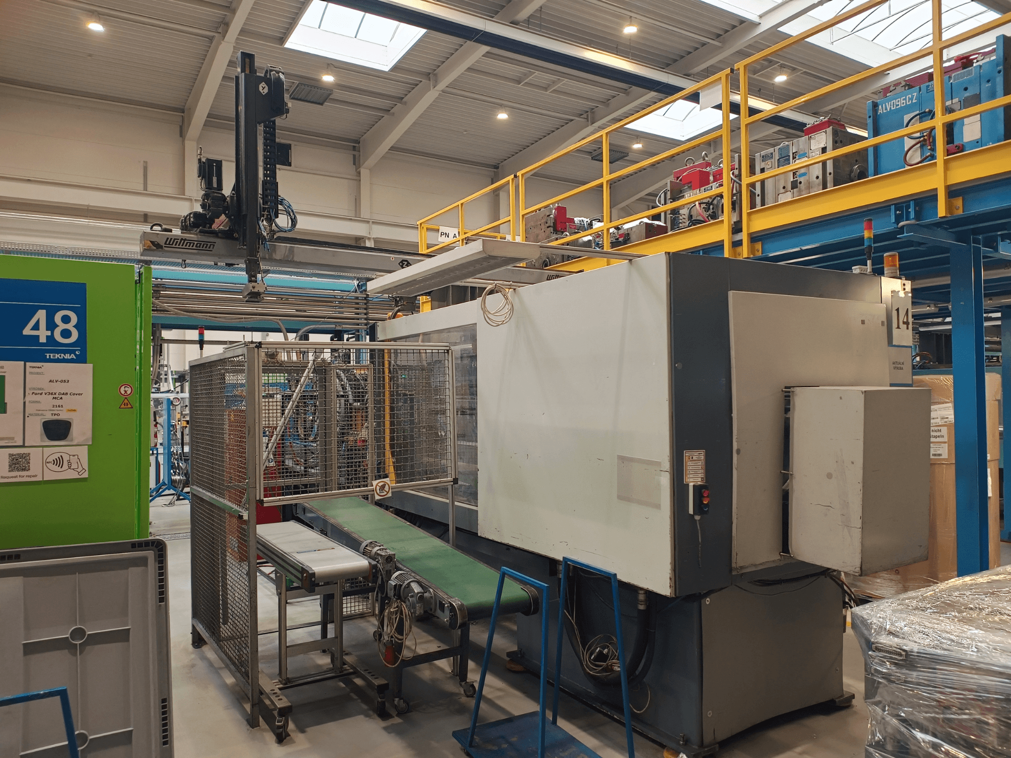 Industrijski automatizacijski stroj tvrtke Winmon, bočni pogled koji prikazuje transportnu traku, upravljačku ploču i sigurnosni kavez u tvorničkom okruženju.