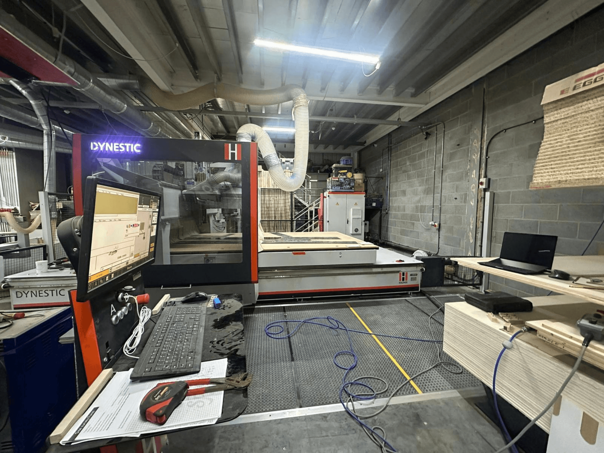 HOLZHER Dynestic 7535 pilana za drvo u radionici, s prikazom upravljačke ploče, monitora i materijala na radnom stolu, pogled sprijeda.