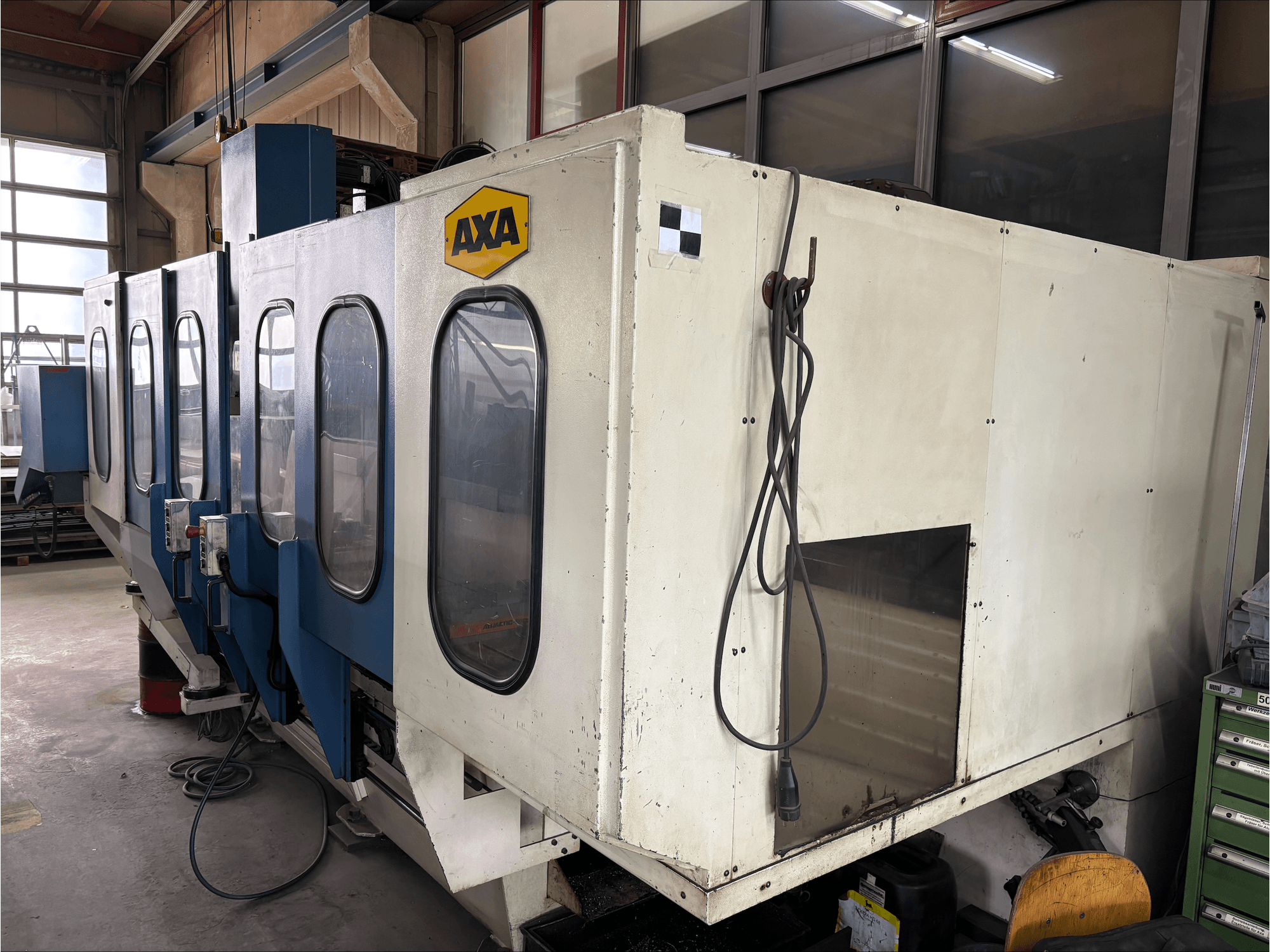 Vertikalni obradni centar AXA VSC-1-M/C, prednji pogled, s velikim bijelim ormarom i plavom upravljačkom pločom.