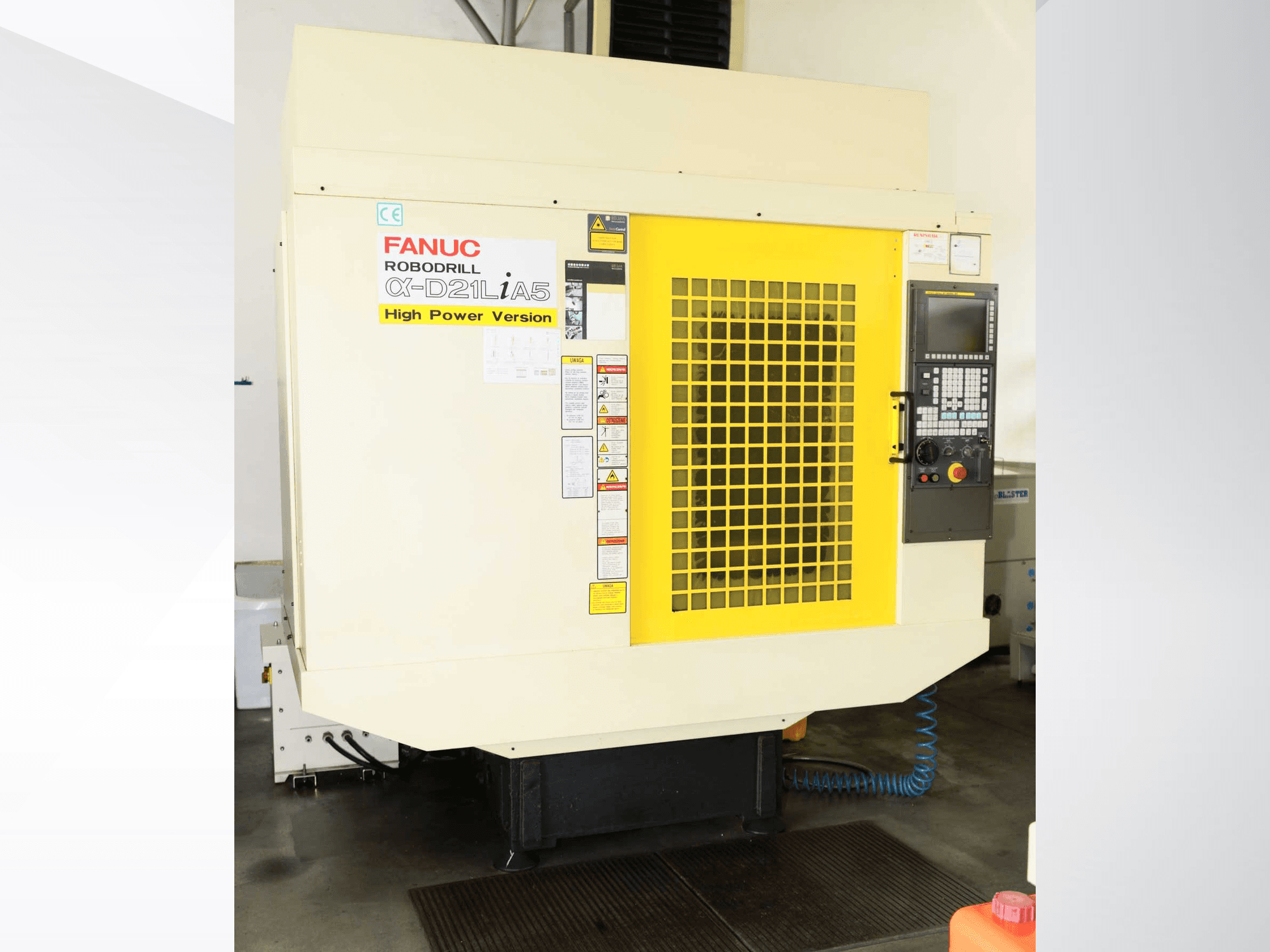 Vertikalni obradni centar FANUC ROBODRILL α-D21LiA5, prednji pogled sa žutom sigurnosnom rešetkom i detaljima upravljačke ploče.