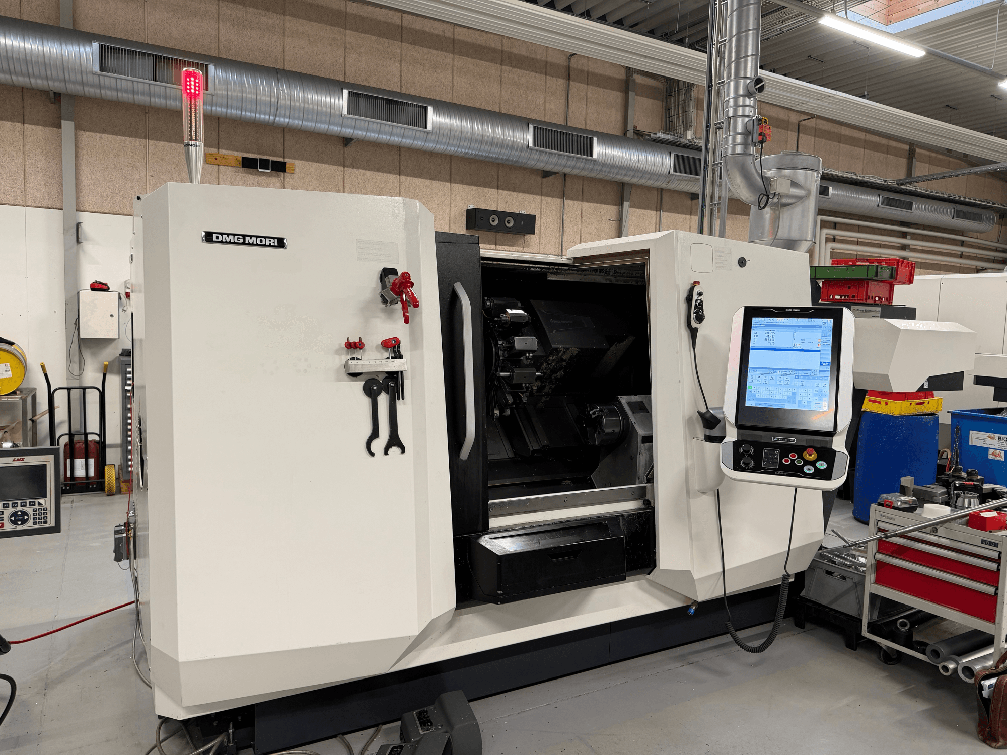 DMG MORI CLX 450 V6 horizontalni tokarski stroj, prednji pogled s vidljivom upravljačkom pločom, sigurnosnim zaustavljanjem i sigurnosnim svjetlom.
