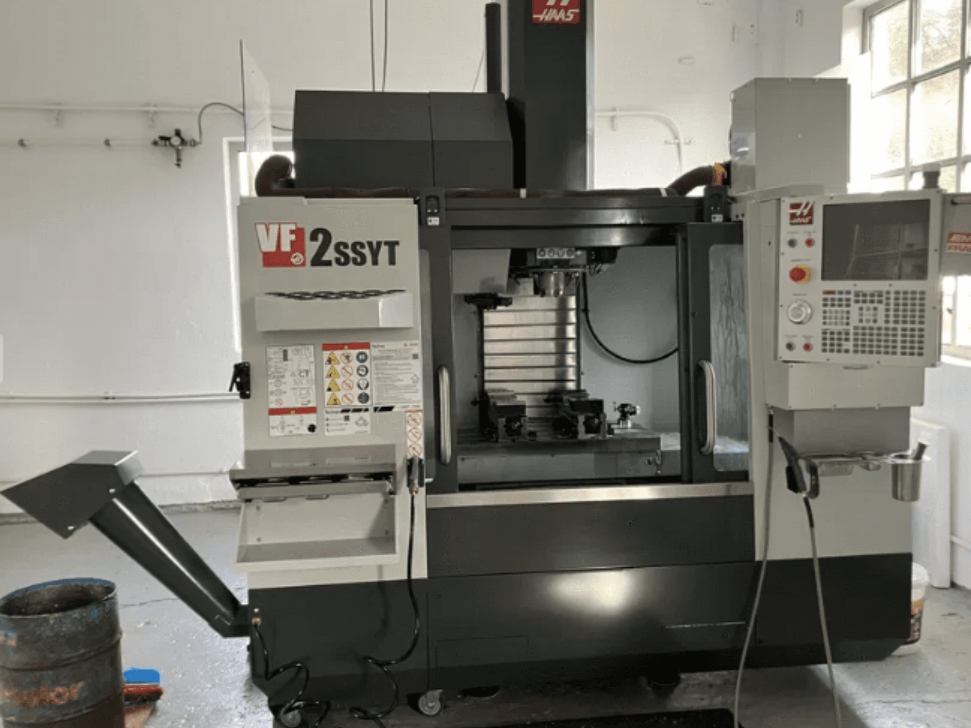 Haas VF-2SSYT CNC glodalica, prednji pogled, sadrži upravljačku ploču, držač alata i sustav hlađenja za obradu metala.