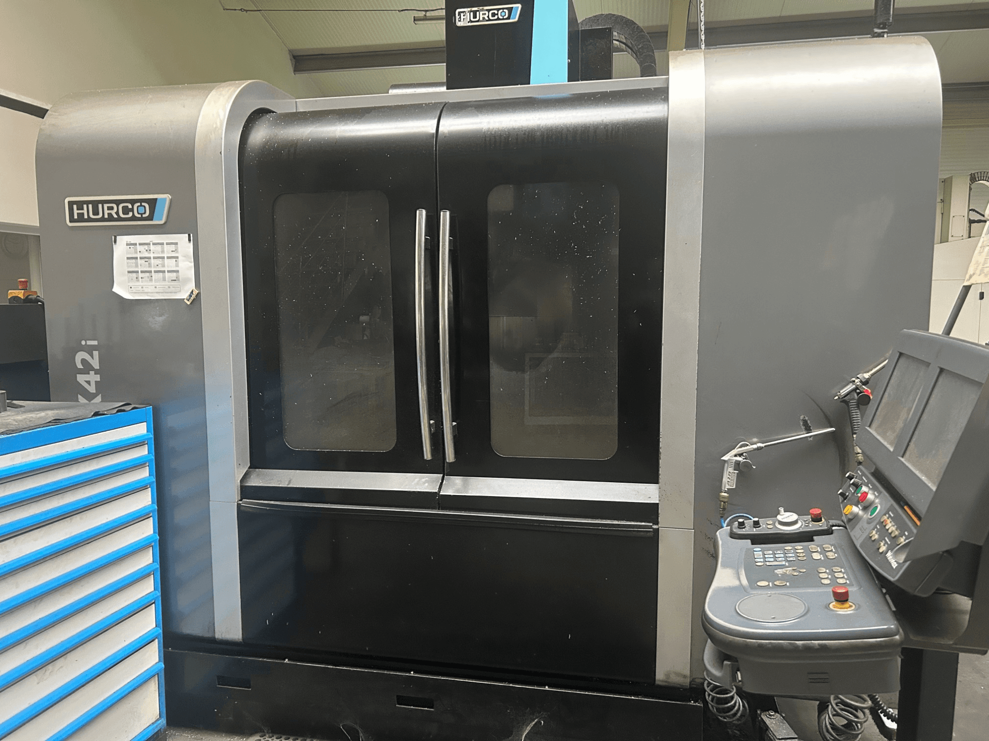 Hurco VMX42i CNC stroj, prednji pogled s upravljačkom pločom sa strane, ima dvostruka vrata i vidljive tehničke detalje.
