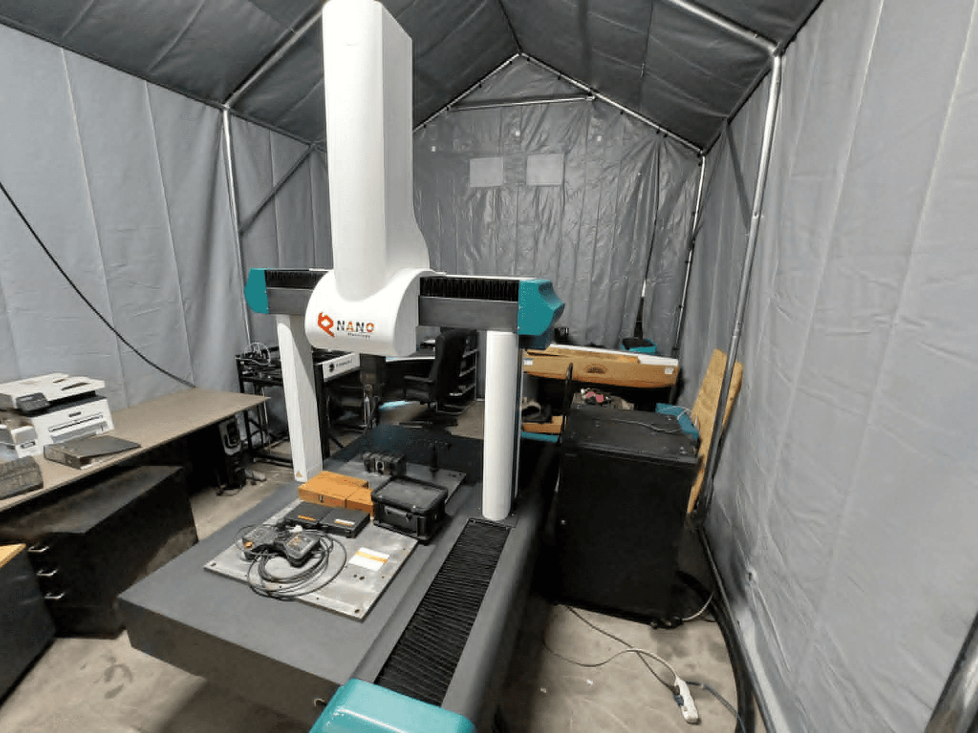NANO METROLOGY Micr 7106 CMM u šatoru; prednji pogled koji prikazuje ruku stroja i mjernu platformu s priborom.