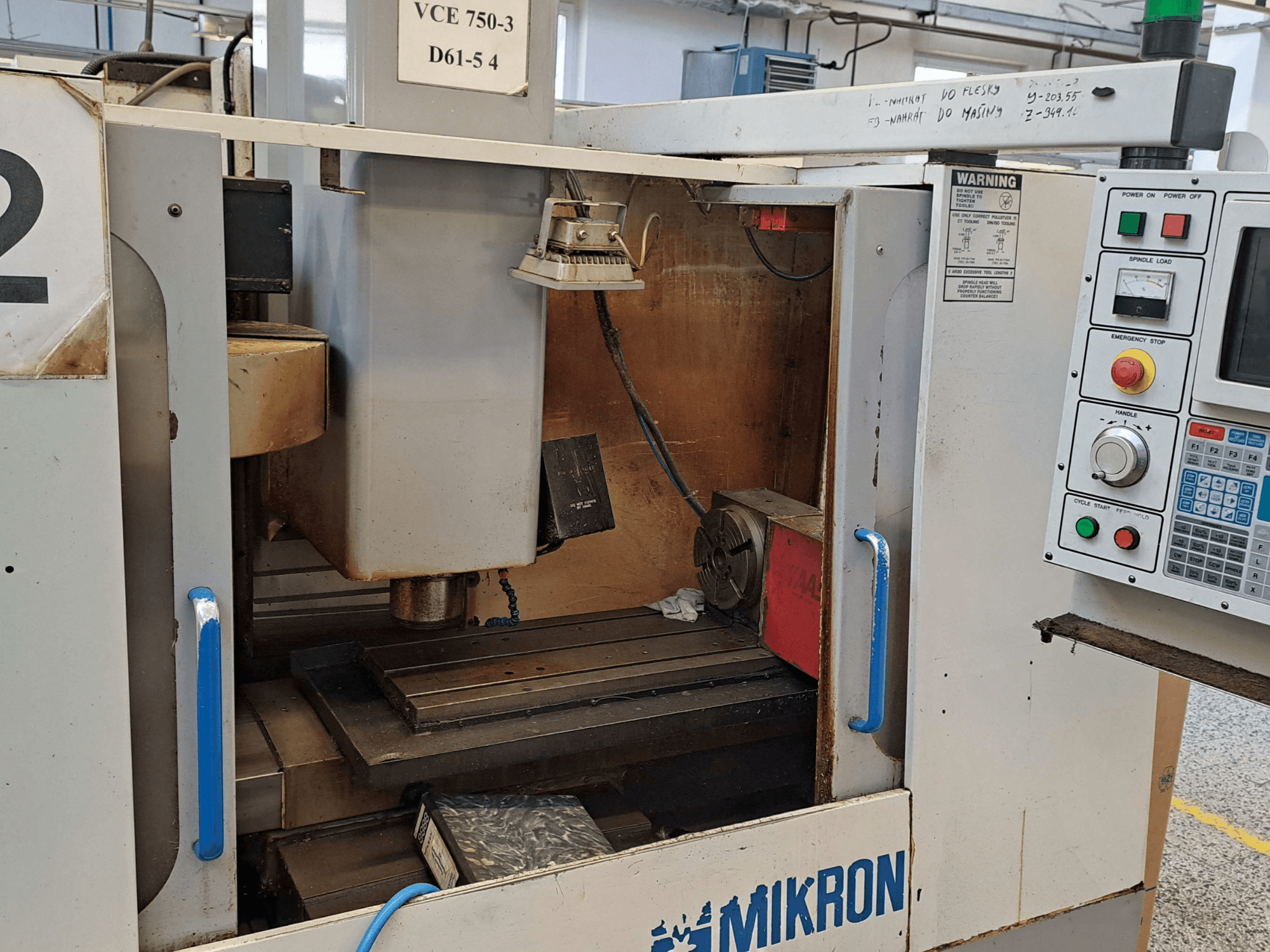 Prednji pogled na glodalicu Mikron VCE 750-3, s prikazom vretena, upravljačke ploče i radnog stola s tehničkim detaljima.
