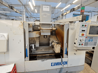 CNC glodalica Mikron VCE 750-2, pogled sprijeda, s upravljačkom pločom i vretenom u području obrade, pokazuje tragove istrošenosti i prljavštine.